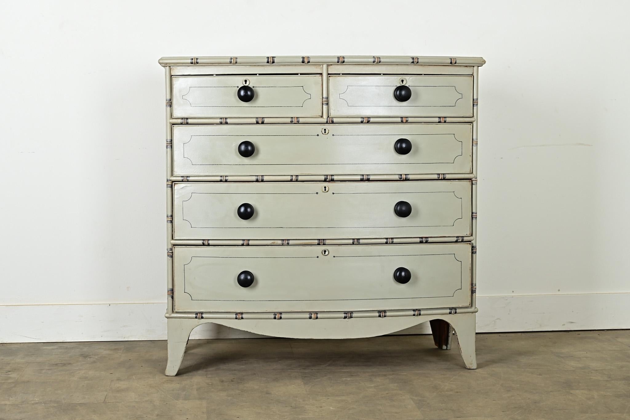 An English bow front chest made in the Regency period with faux bamboo detailing. Pearl gray paint gives a fresh and light update to the classic silhouette, offering five drawers for storage. The bamboo-effect trim is accentuated at the nodes with
