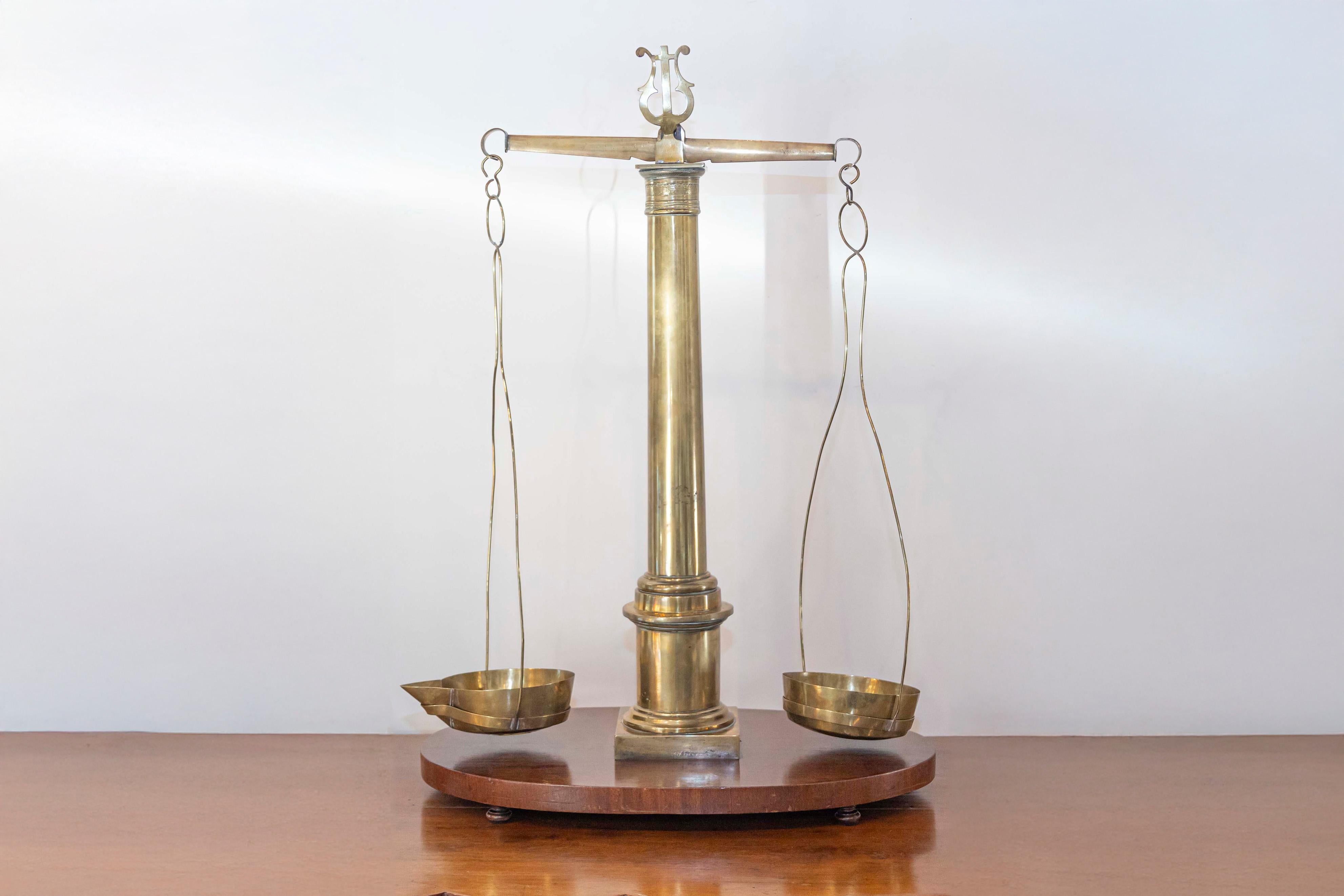 Balance d'herboriste anglaise en laiton du XIXe siècle, avec des détails de colonne et de lyre, montée sur une base en bois. Utilisée pour mesurer les herbes, cette exquise balance comporte une structure en laiton présentant une colonne centrale