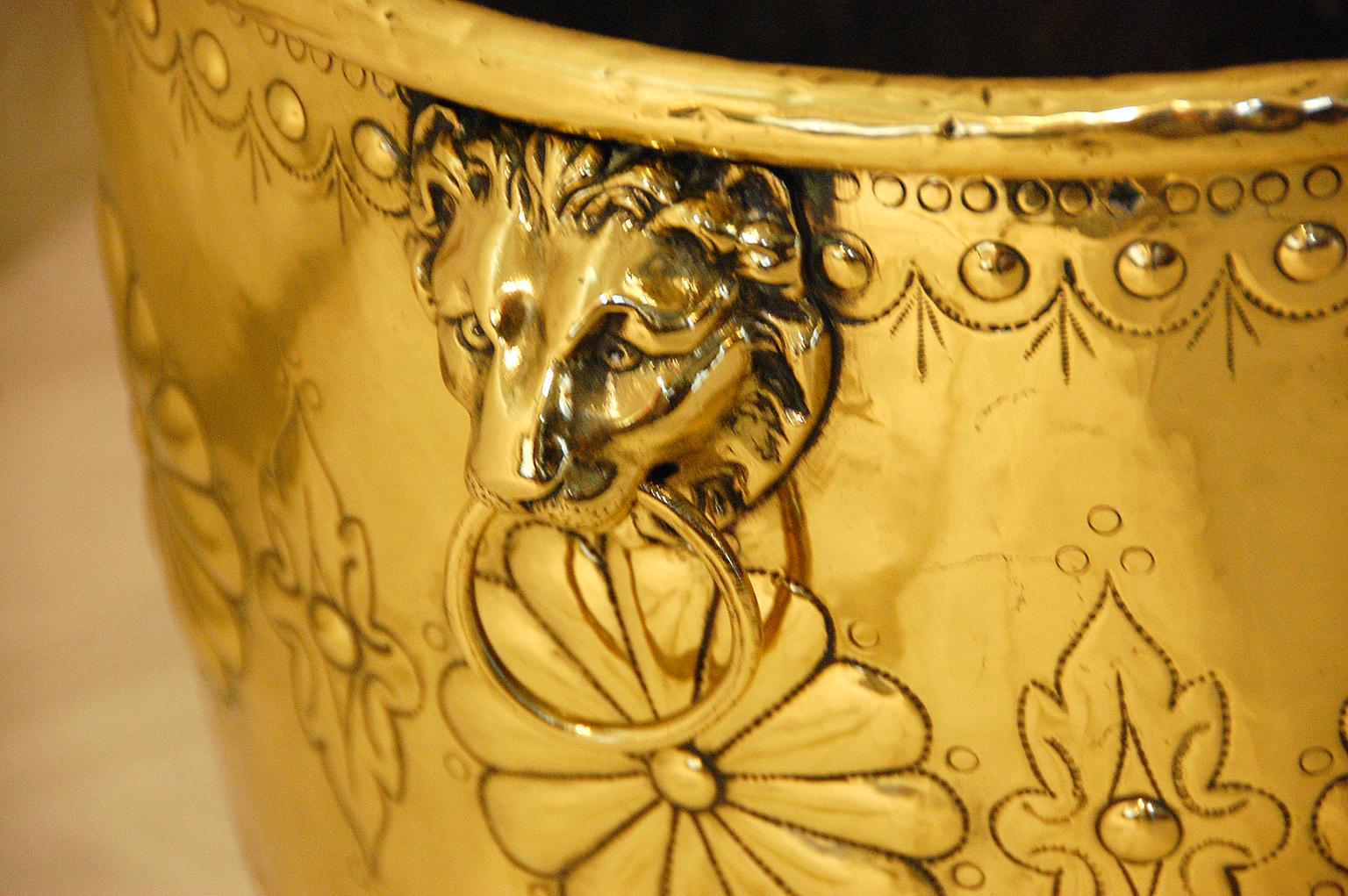 English 19th century brass jardinière or log bin with repousse decoration and lion side handles. 16 Inch diameter (not including handles) and 14 1/2 inches high make it the perfect size for next to a fireplace.