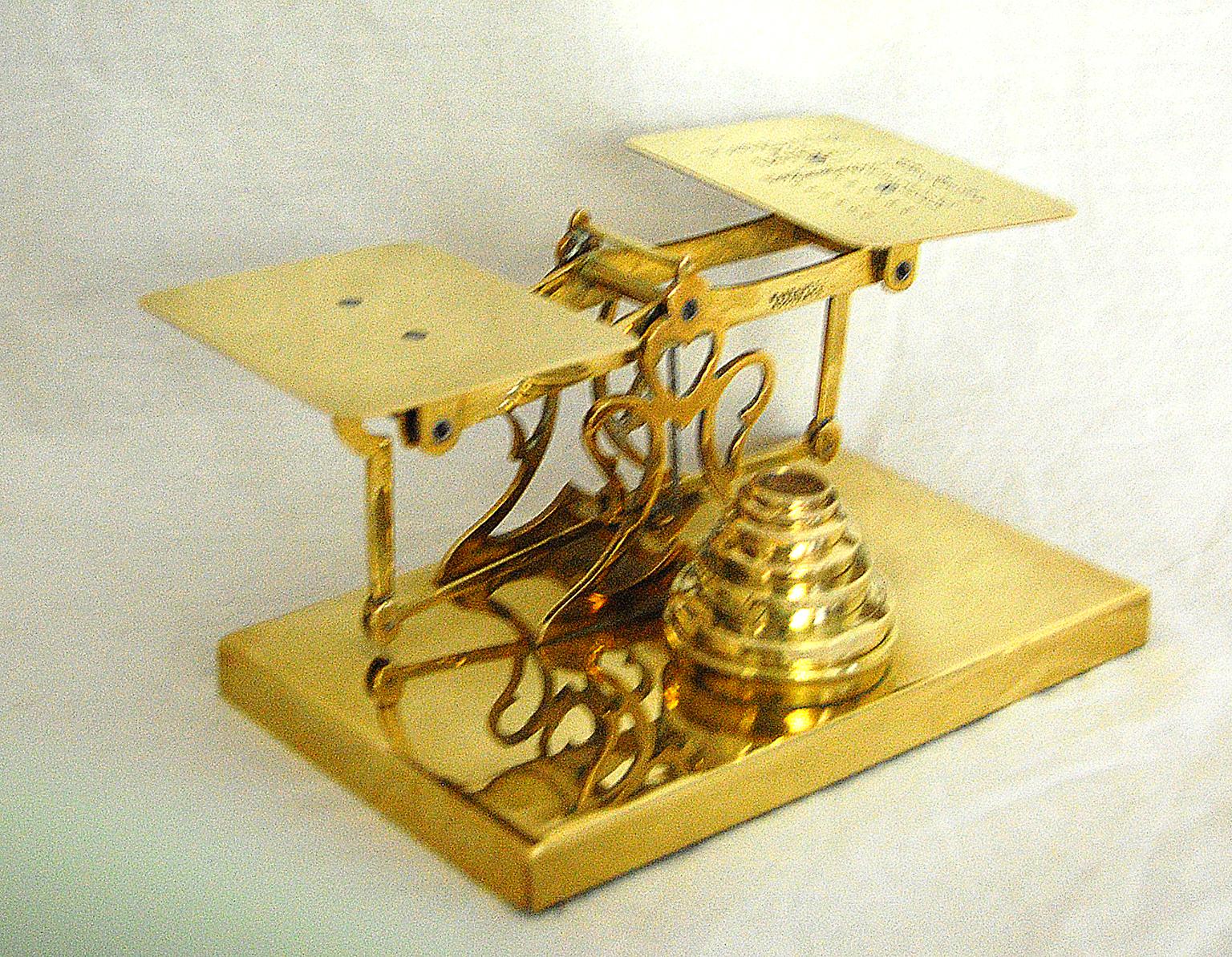 English 19th century brass postal scale on brass base by Sturner and Sons, postal rates for letters are engraved on one balance pan, signed with Sturner's emblem. There are 6 assembled brass stacking weights from various makers: 8 oz, 4 oz, 2 oz, l