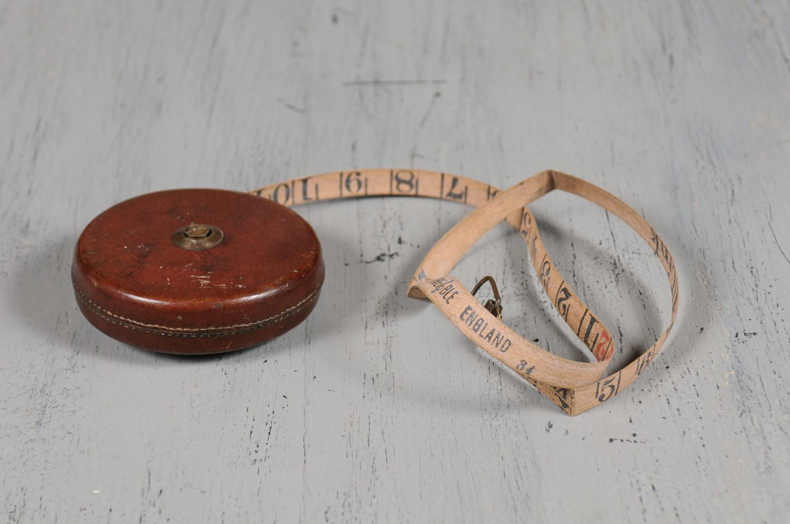 An English leather case 50 feet retractable tape measure from the 19th century marked Treble England. Born in England during the 19th century, this tape measure features a brown leather case with brass winder. Marked 