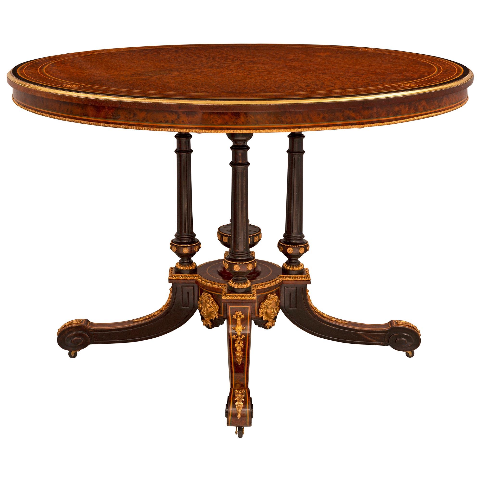 A stunning and extremely decorative English 19th century burl Walnut, Maplewood, Charmwood, and ormolu tilt top center table signed Edwards & Roberts. The circular table is raised by elegant lightly curved legs with their original casters and