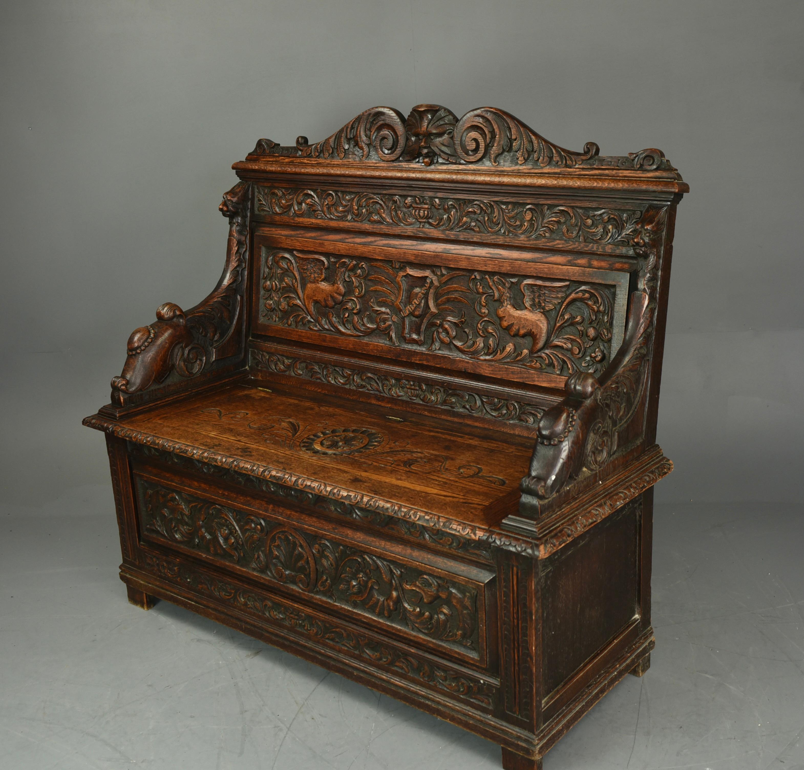 Stunning carved oak settle hall seat. The quality of the carving is excellent with the front, arms and back rest all profusely decorated.The back with carved oak green man crest The lift up seat to provides storage for boots, shoes, bags etc. This