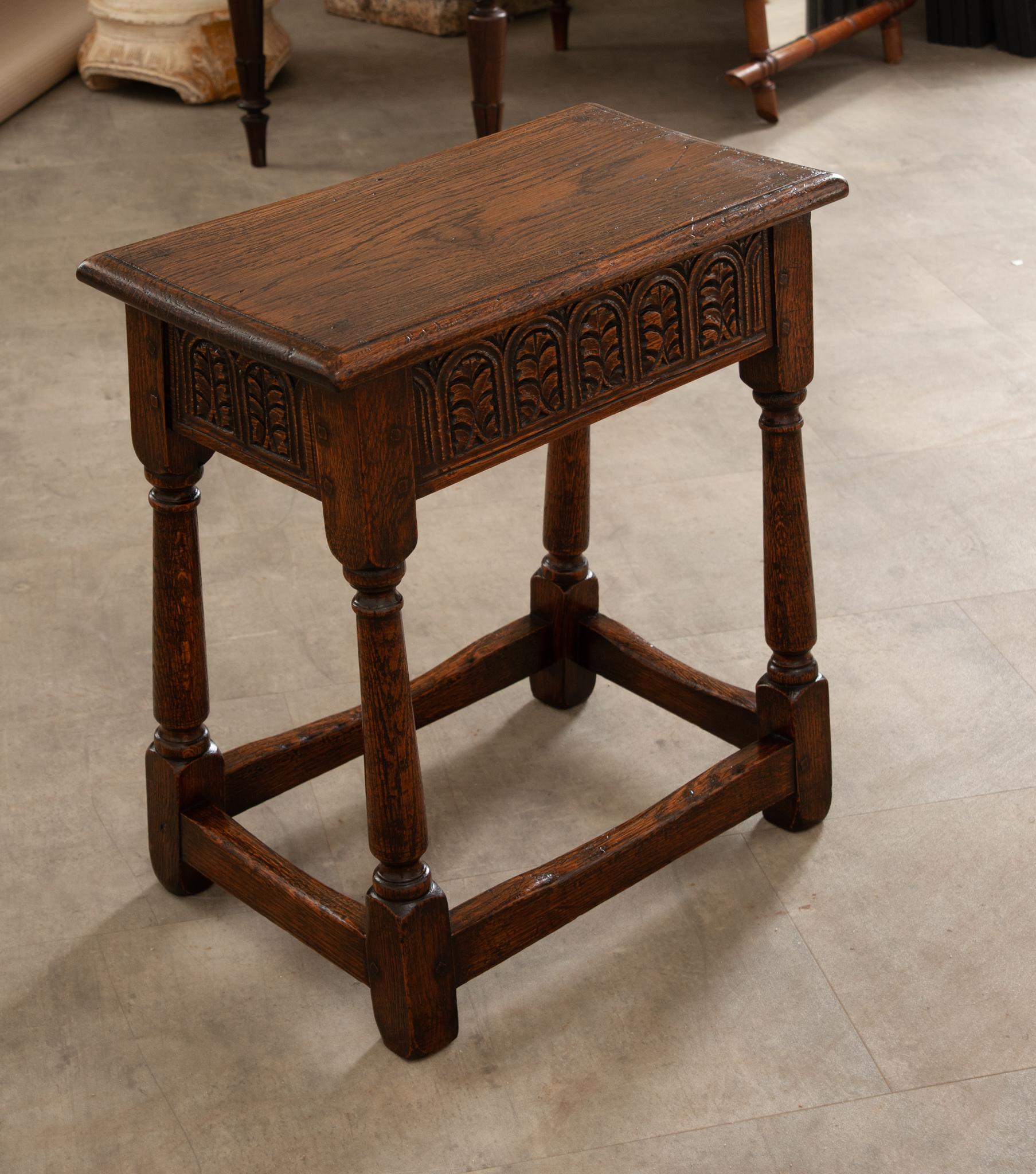 A wonderful oak joint stool made in England in the 19th century featuring a simple top that has a molded edge following down to wonderfully hand carved aprons with foliage pattern decoration on all four sides which allows for easy placement in any