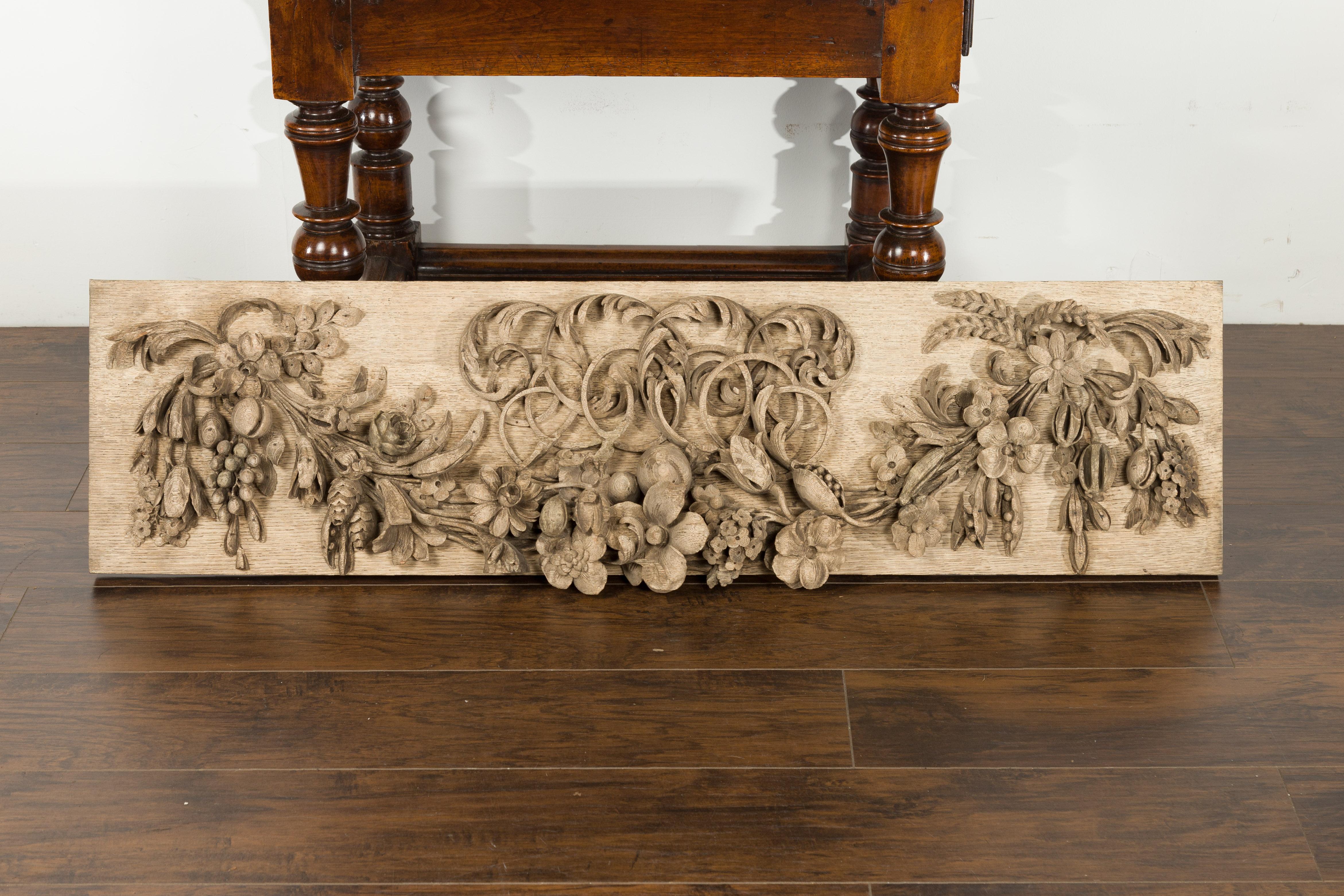 An English carved wooden fragment from the 19th century, with fruits and flowers garland. Created in England during the 19th century, this horizontal fragment captures our attention with its skillful carving and natural patina. The panel is adorned