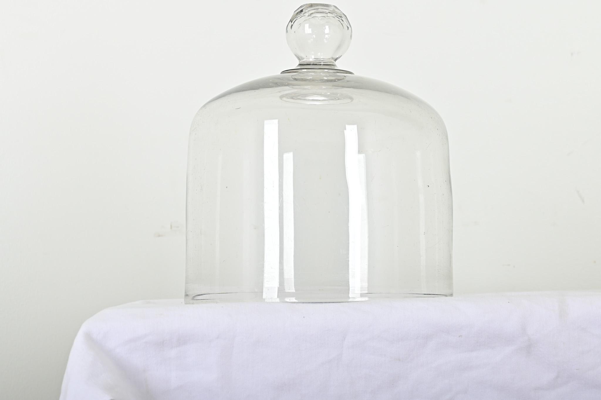 An English hand blown and faceted glass dome used for covering cheese or pastries, most likely for display in a mercantile shop. The cut glass knob elevates the design for everyday use and special occasions. A small chip is visible at the bottom