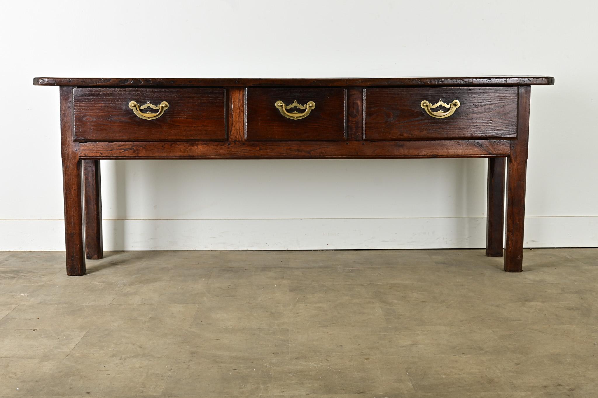 This unpretentious console table, or server, was hand-crafted of solid chestnut in England, circa 1820. The thick planks of the top have incredible texture, a rich patina, and chamfered corners. Within the large apron are three deep drawers opened
