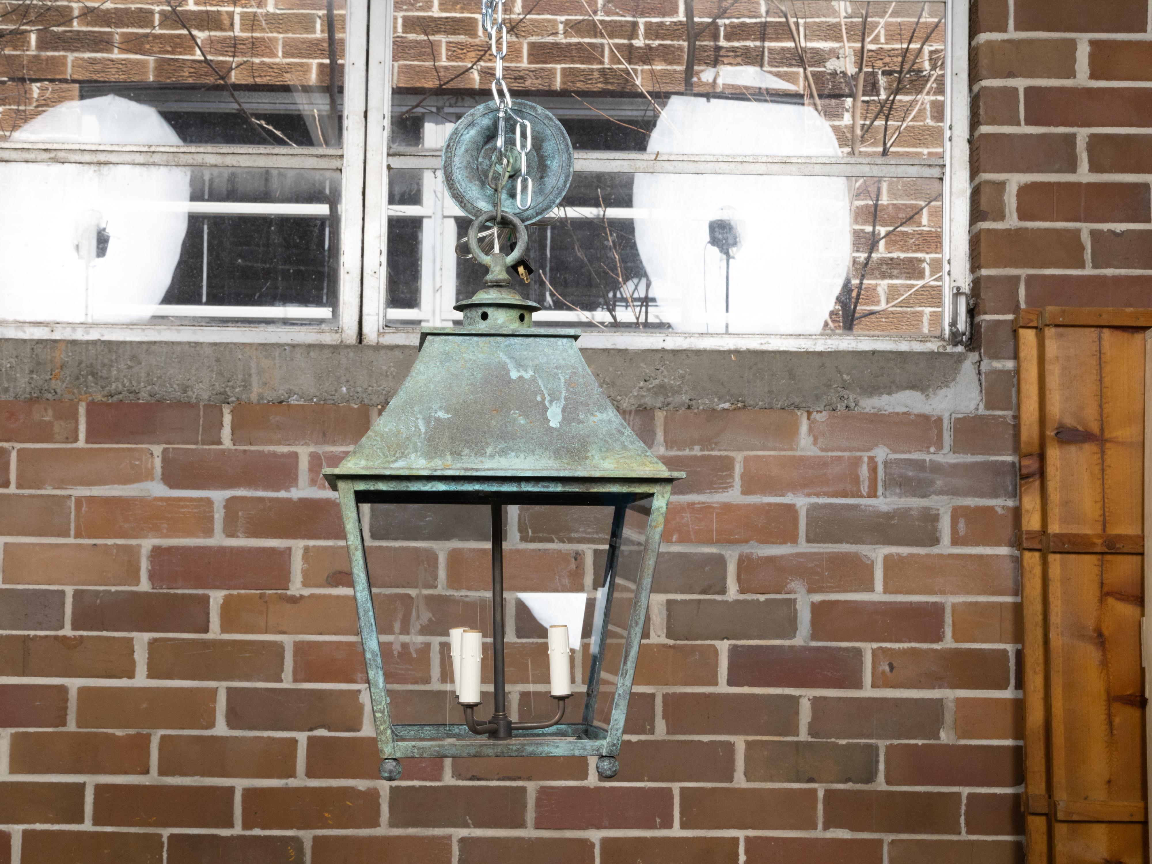 An English copper lantern from the 19th century with glass panels and verdigris patina. This 19th-century English copper lantern, exquisitely showcasing a verdigris patina, brings a piece of historical elegance into the modern home. The lantern's