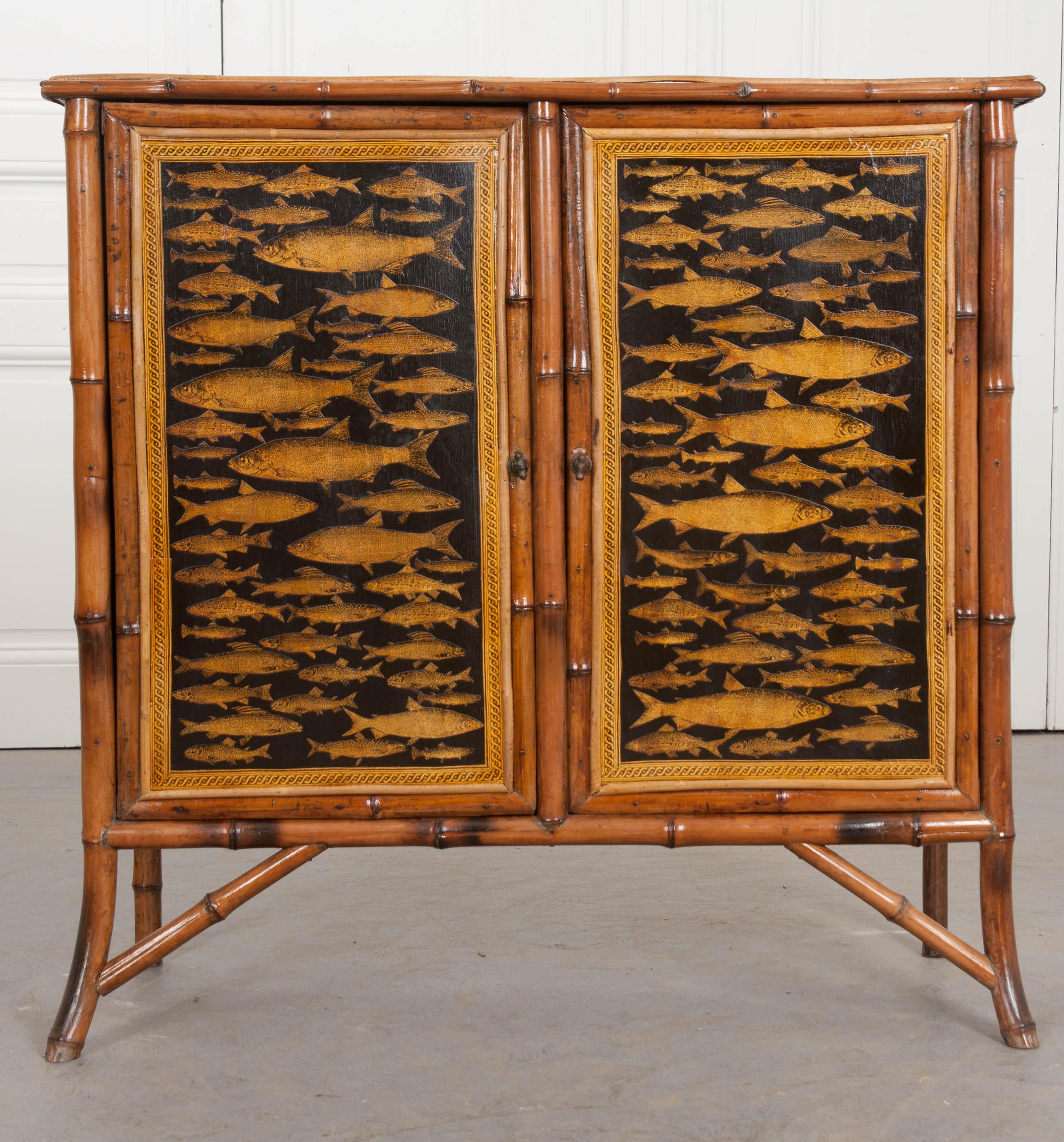 A wonderful 19th century English bamboo cabinet with two doors and recently découpaged fish front, sides and top. The doors latch closed before an interior storage compartment. It is outfitted with two fixed shelves. The cabinet is sized wonderfully