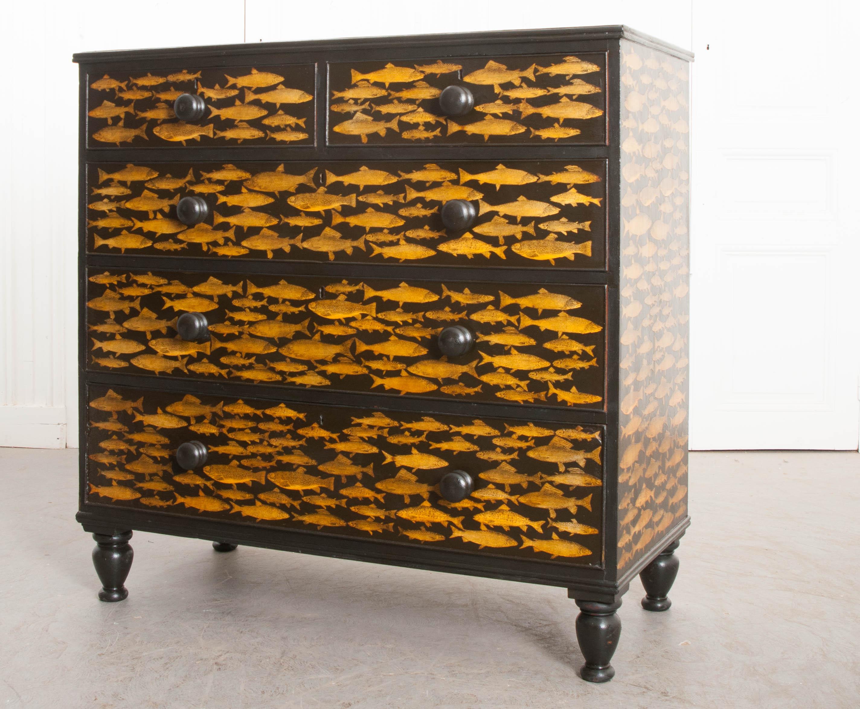 This delightful English pine chest, circa 1880s, has recently been ebonized and découpaged in a fun fish motif. It features a pair of short drawers over three long drawers, each with turned pulls. The whole is supported by bulbous turned feet. This