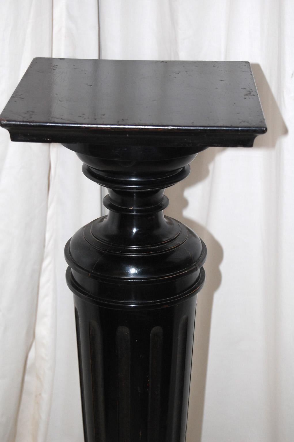   English ebonized late 19th century torchere.  This turned and tapered column on square base is reeded and has interesting turnings framing the tall column.  At 44