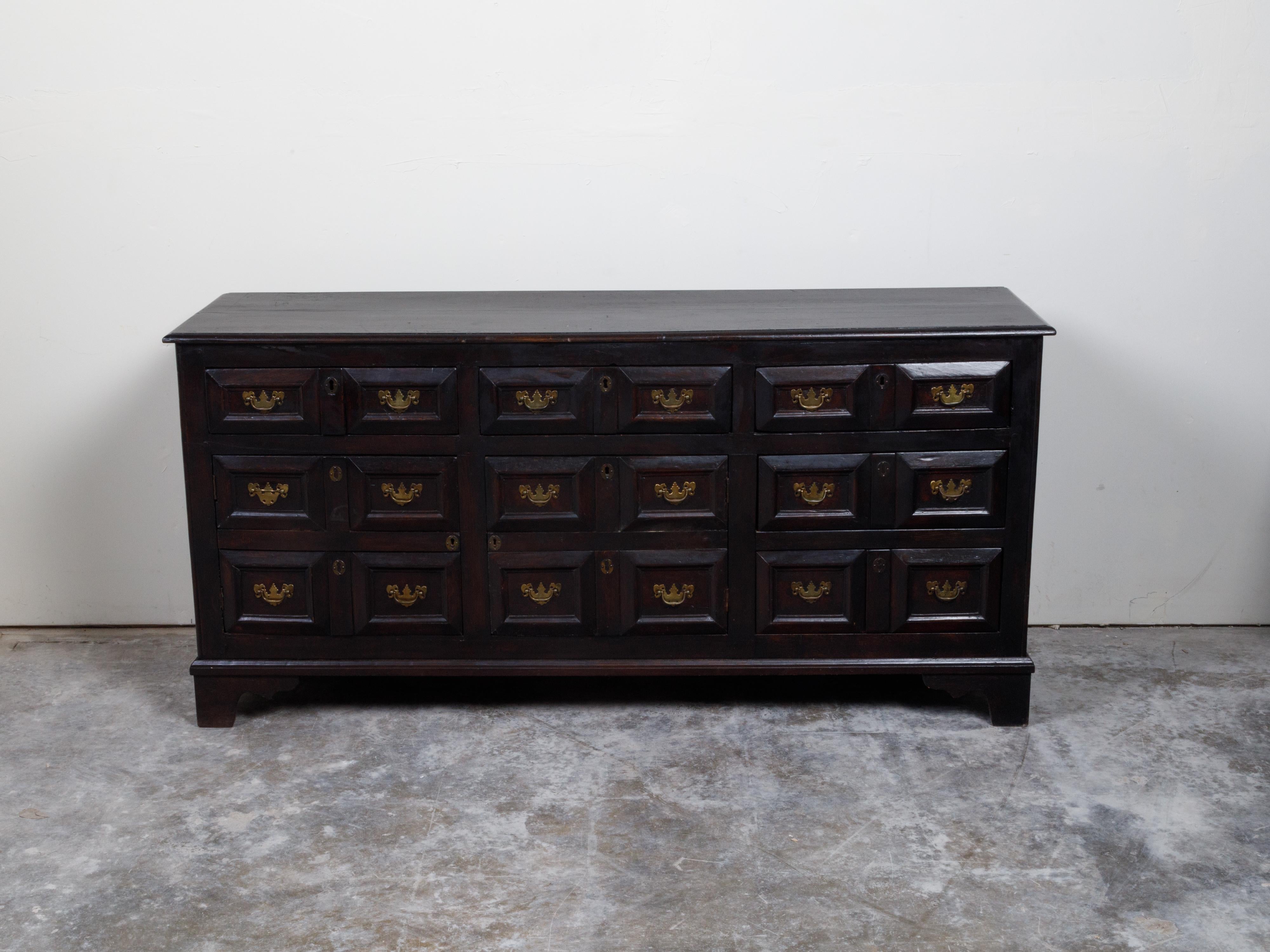 An English ebonized wood buffet from the 19th century, with doors and drawers. Created in England during the 19th century, this buffet features a rectangular top with beveled edges sitting above a perfectly organized combination of doors and