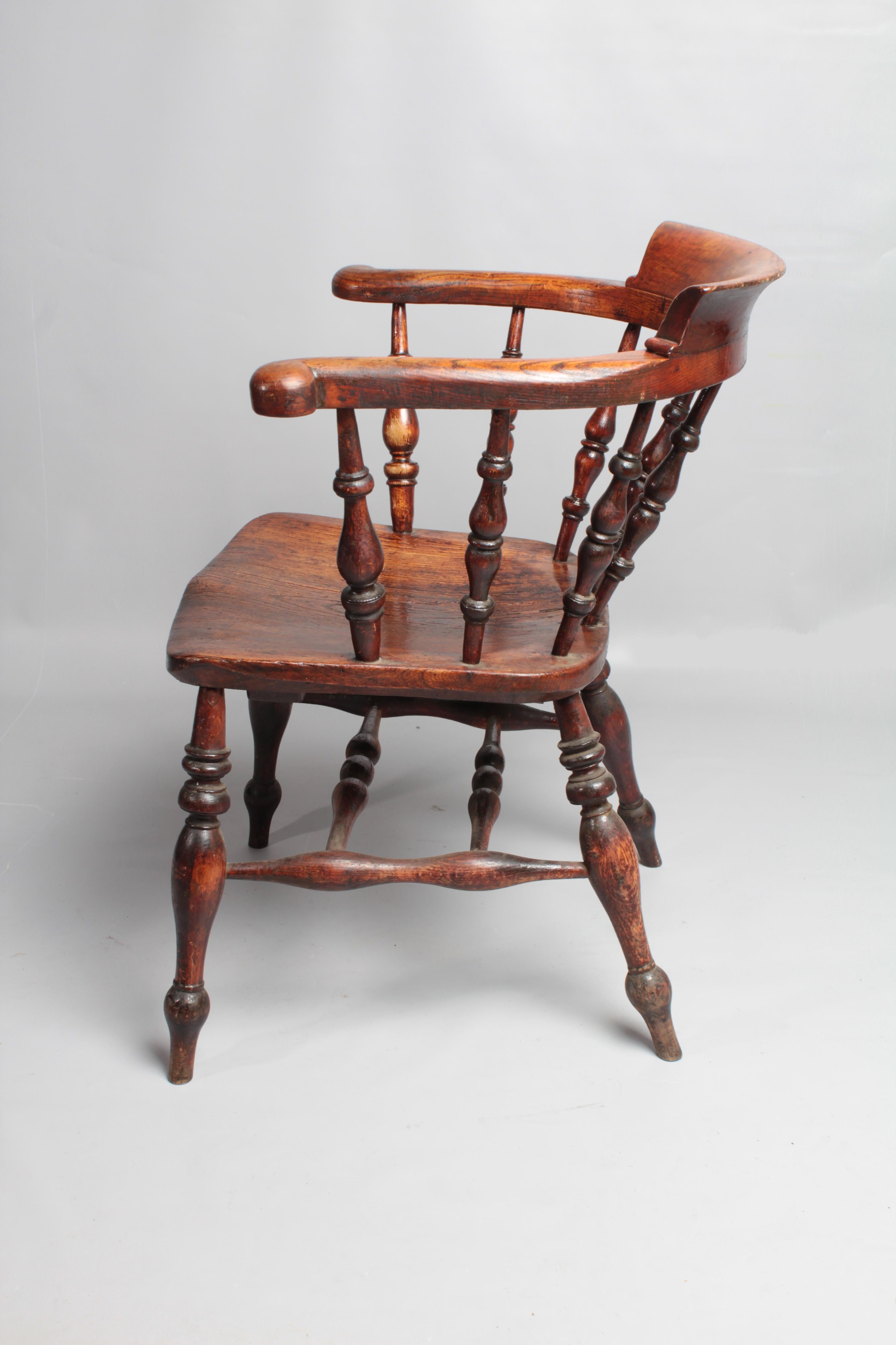 Victorian, spindle bow back 'Smoker's' or 'Captain's' chair.
Aged elm patina with good grain detail in the saddle seat slab. Baluster legs with a double 'H' stretcher and turned spindles supporting the horseshoe armrest and out-turned scrolled hand