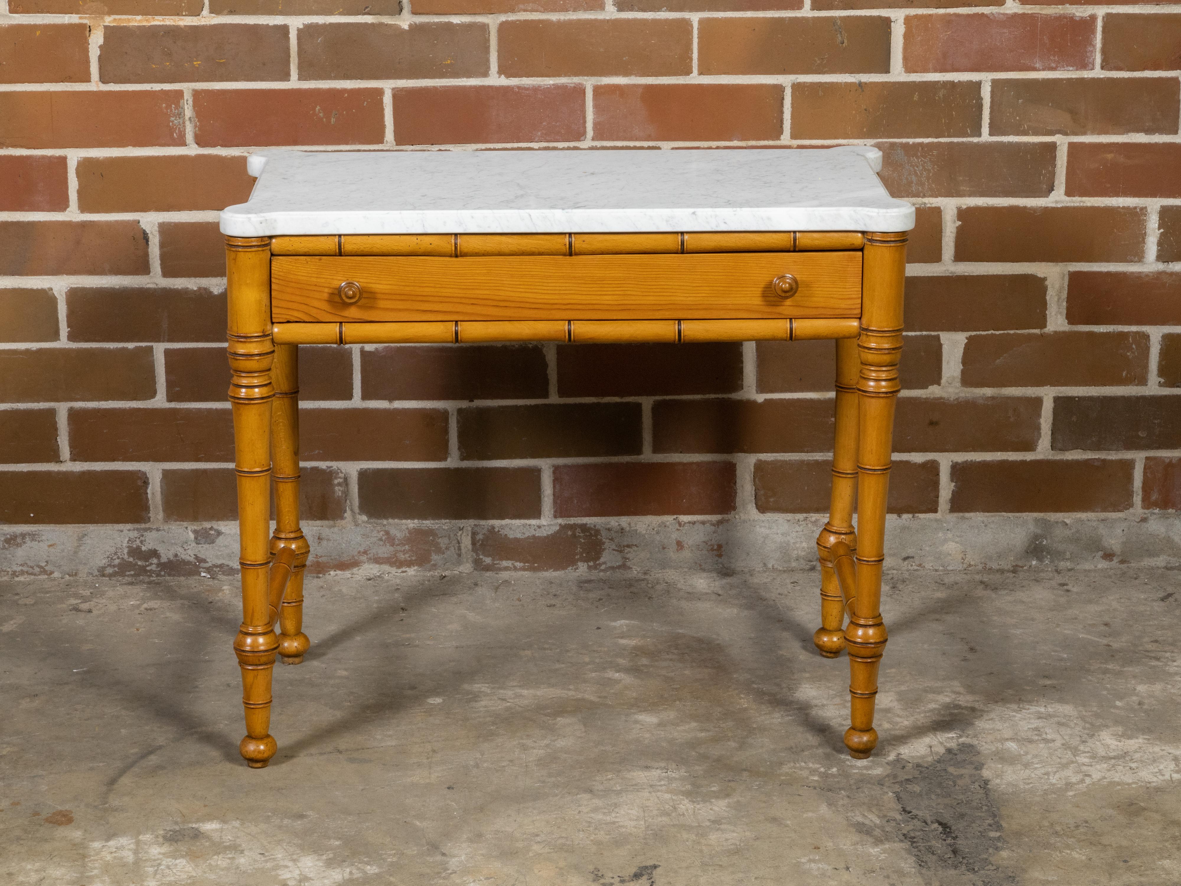 An English faux bamboo console table from the 19th century, with white marble top, single drawer, side stretchers and petite ball feet. Created in England during the 19th century period, this console table features a rectangular white marble top