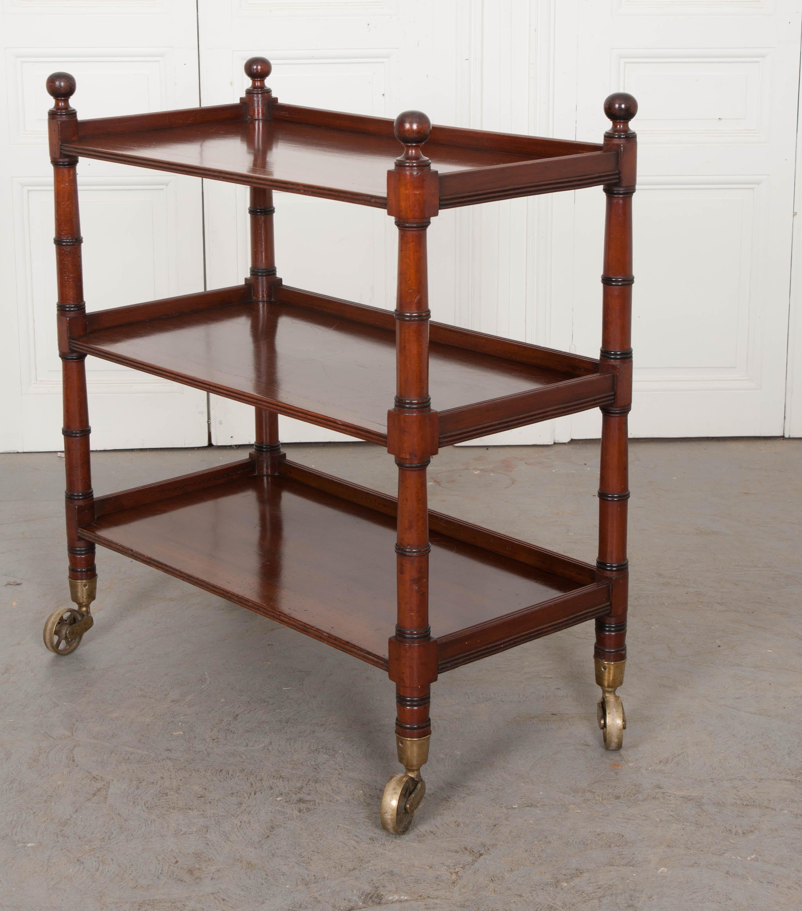 Sometimes referred to as a “dumb waiter” or “tea cart”, this antique is a top-quality English faux bamboo-carved three tier mahogany tea trolley, circa 1870s, is from the estate of Michael Gray, c. 1865.  The mahogany used to create this wonderful