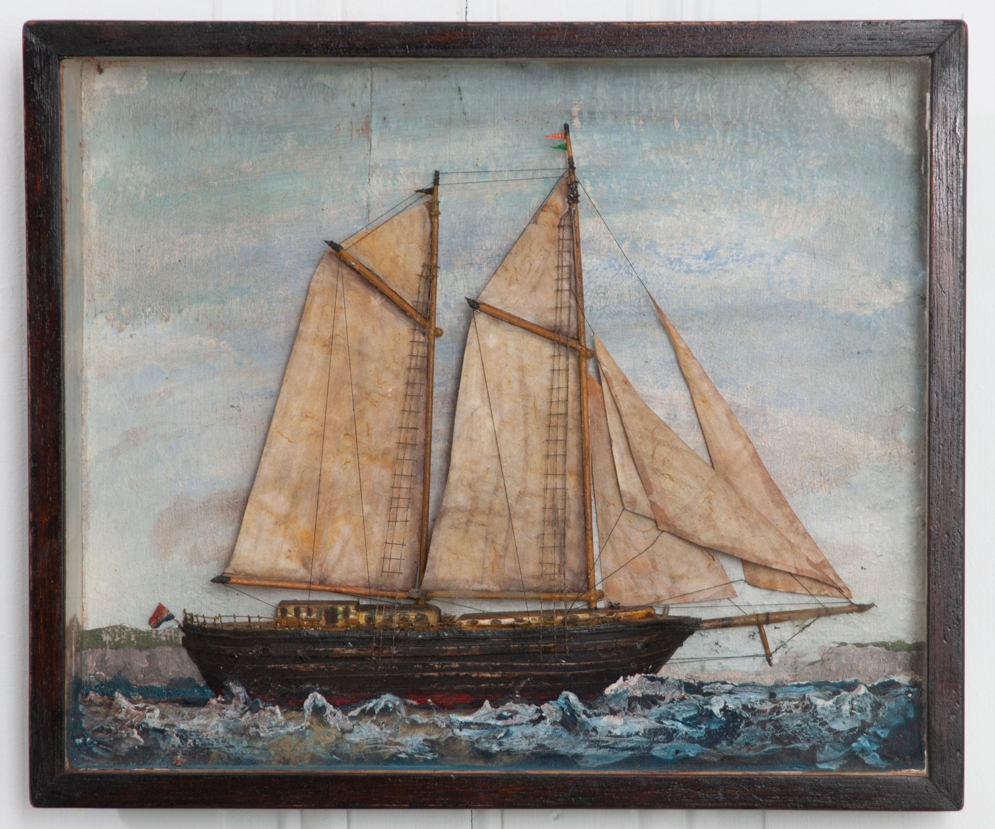 A brilliant English 19th century nautically themed diorama featuring a schooner. These three dimensional works of art were typically made by sailors in the 19th century. Encased behind glass, this diorama depicts a schooner at sea near a clif faced