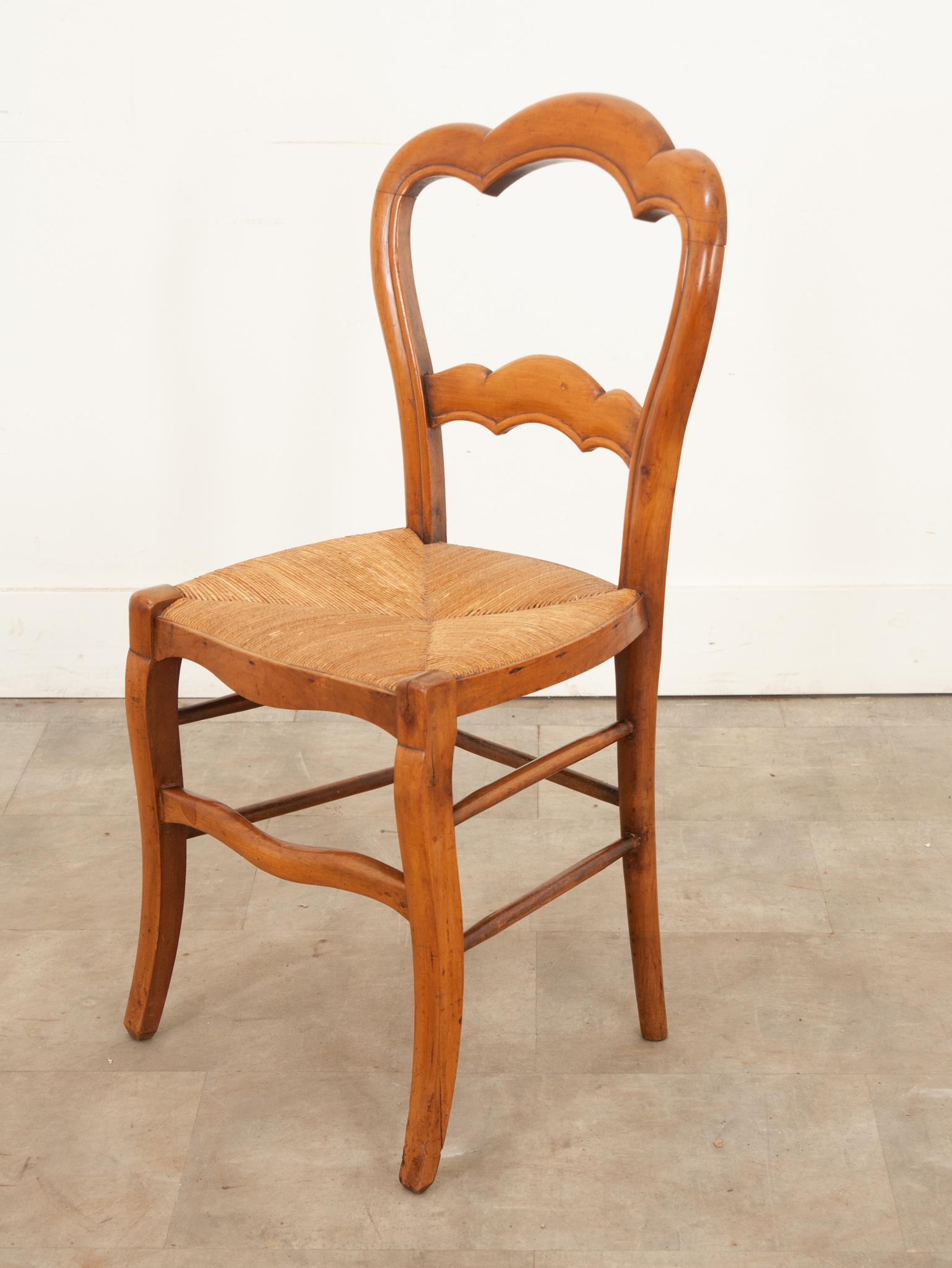 Chaise anglaise du 19ème siècle en bois fruitier avec une assise en jonc. Cette chaise a été fabriquée à la main en Angleterre vers 1870 et est tout simplement adorable avec son dossier festonné sculpté et son assise en jonc chaud qui est en très