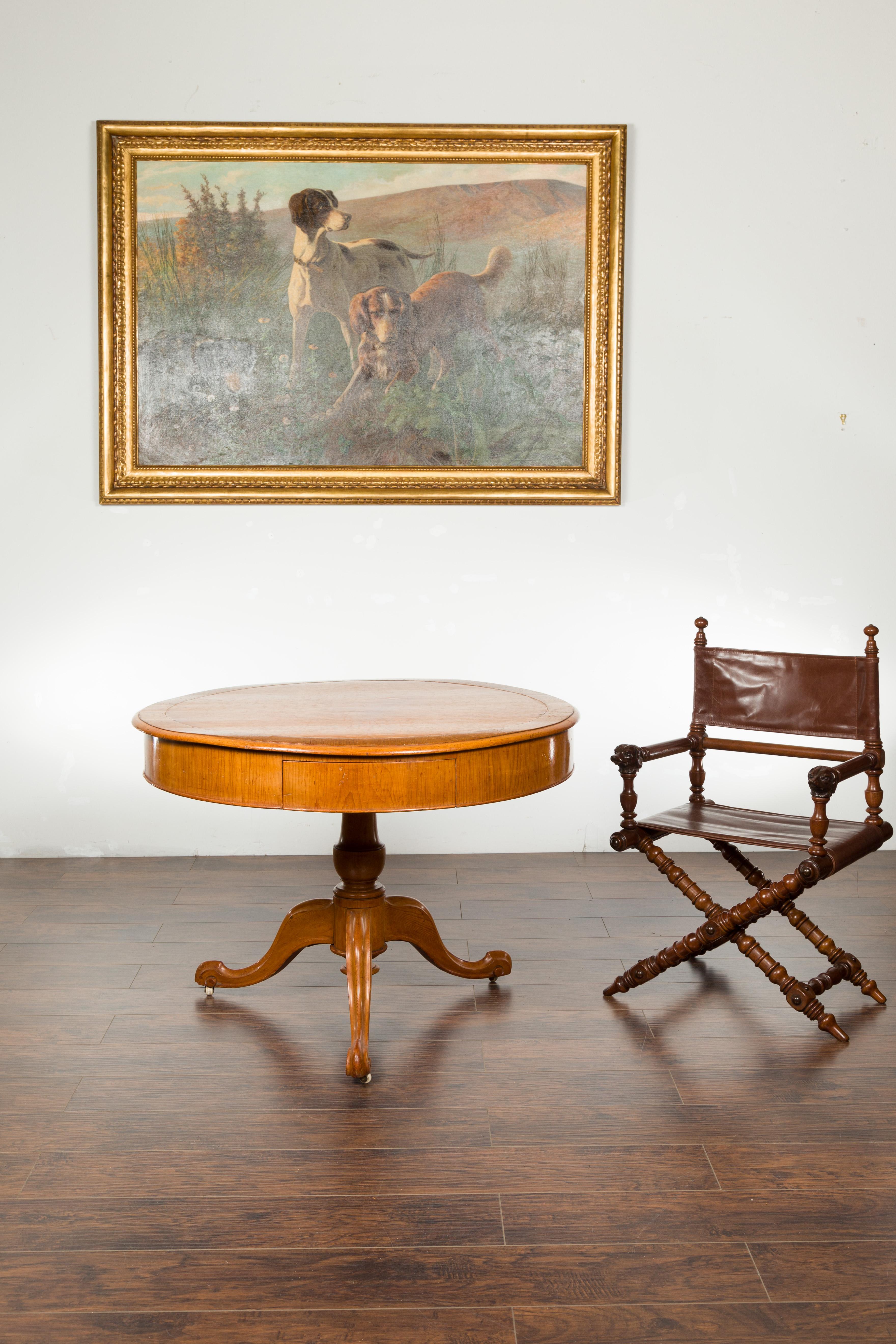 An English fruitwood pedestal table from the 19th century, with leather top, two drawers and cabriole legs. Created in England during the 19th century, this fruitwood table features a circular leather top sitting above an apron showcasing two