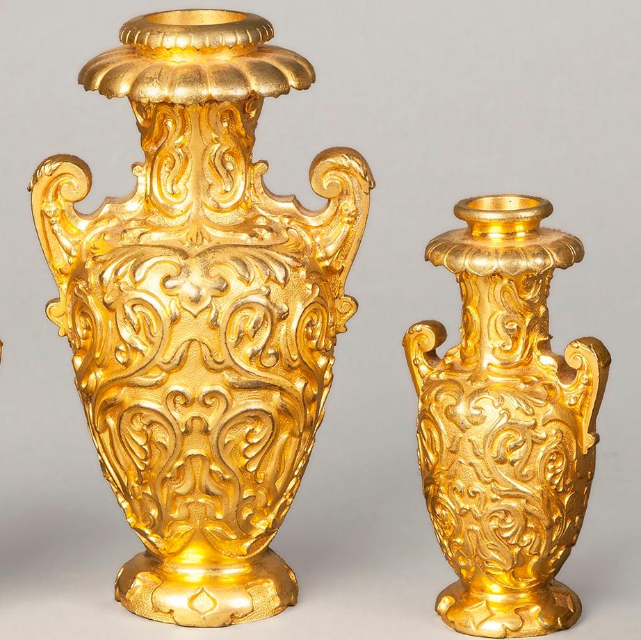 A gilt bronze garniture de fireplace by Elkington and Company

Conceived in the Rococo manner, the gilt bronze being excellently cast and planished, the suite consisting of a central two handled baluster form vase, two similar and smaller, and a