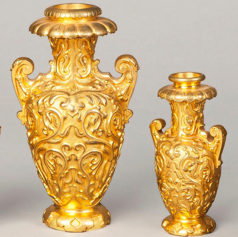 Una guarnitura da camino in bronzo dorato di Elkington and Company

Concepito alla maniera rococò, il bronzo dorato è ottimamente fuso e piallato, la suite consiste in un vaso centrale a due manici a forma di balaustro, due vasi simili e più