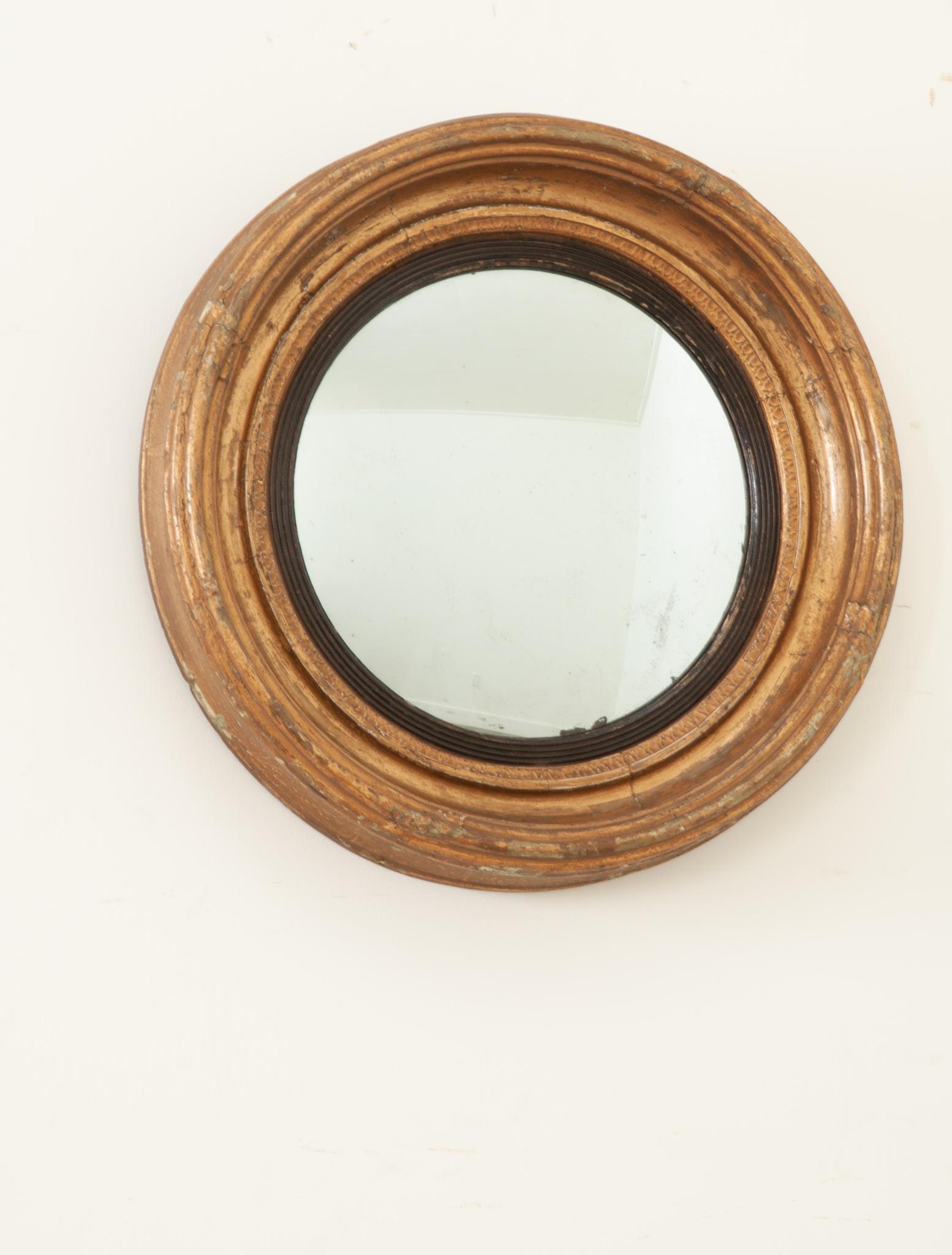 A handsome convex mirror crafted in England during the 1820’s at the end of the Georgian era. The round molded gold gilt frame has a lovely patina and secures the antique mirror plate firmly. The mirror has a slight convex and a clear reflection