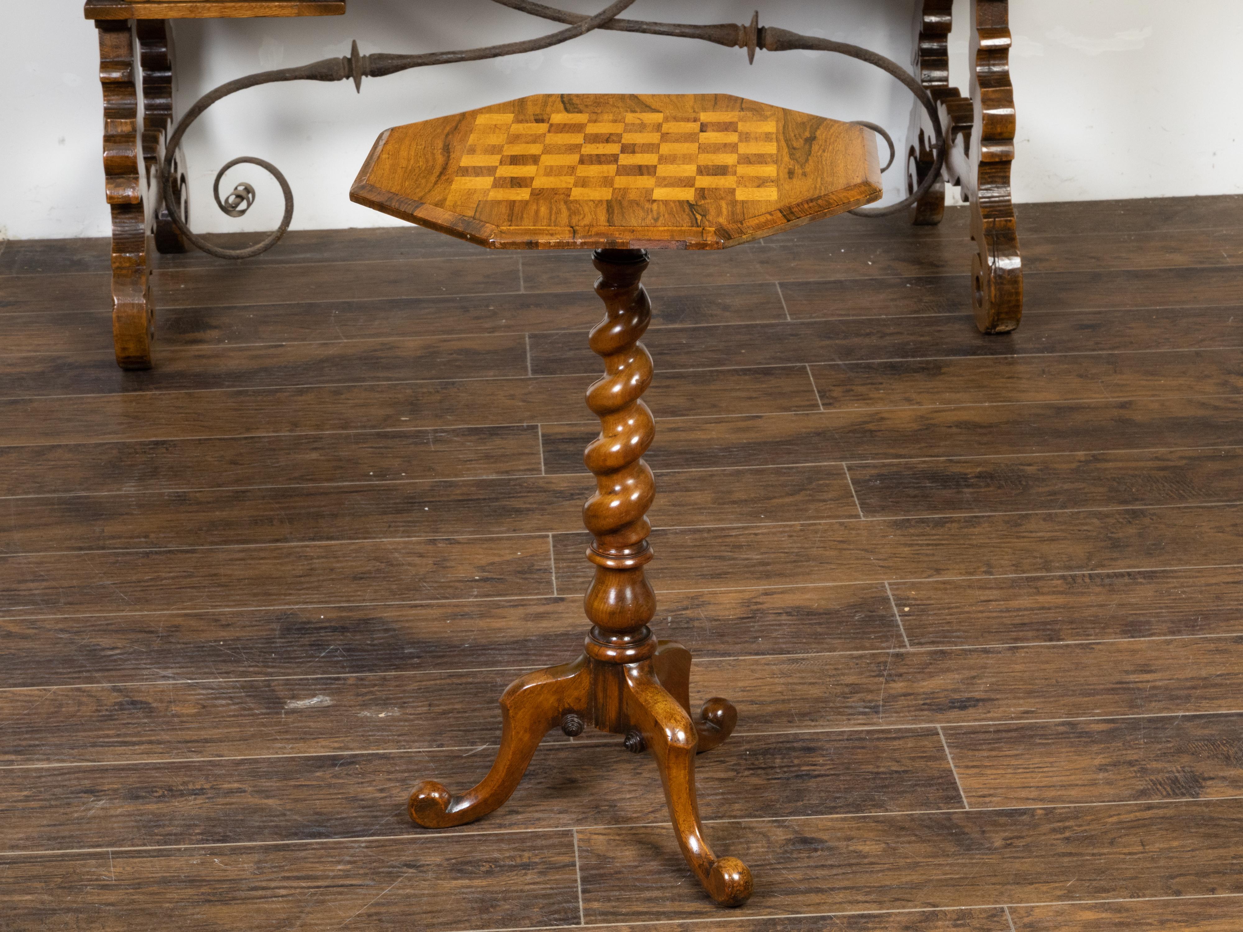 An English wooden guéridon side table from the 19th century, with octagonal top, checkerboard parquetry inlay, twisted pedestal and tripod base. Created in England during the 19th century, this wooden guéridon table features an octagonal top adorned