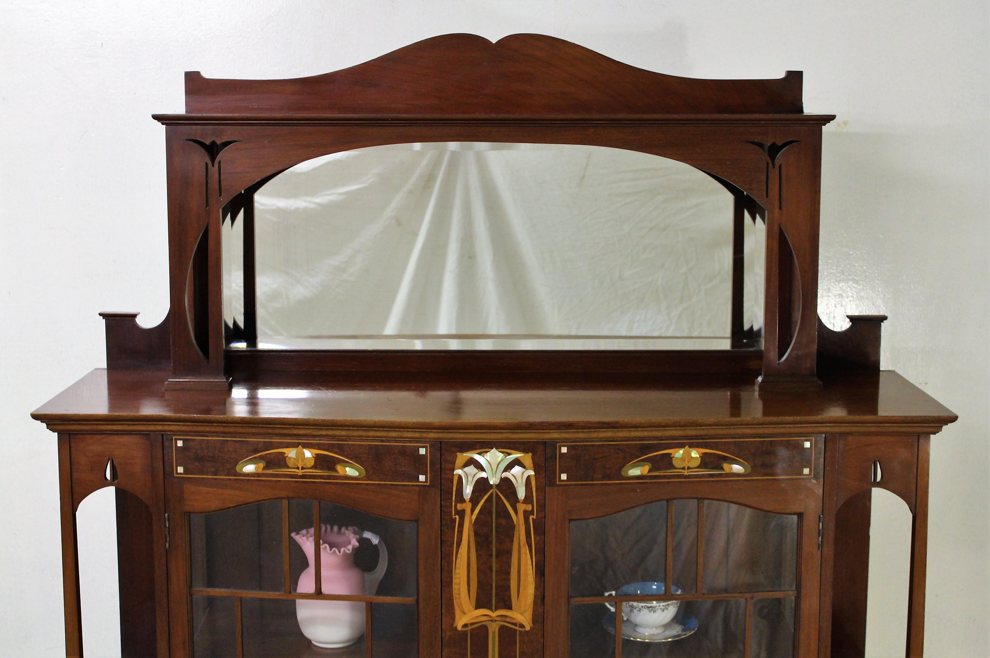 Hervorragende Vitrine aus Mahagoni mit Intarsien aus der Jugendstilzeit, mit vielen Designmerkmalen, die an die damalige Zeit erinnern. Sehr gut konstruiert aus Mahagoni und verziert mit stilisierten, eingelegten Blumenmotiven aus Satinholz,
