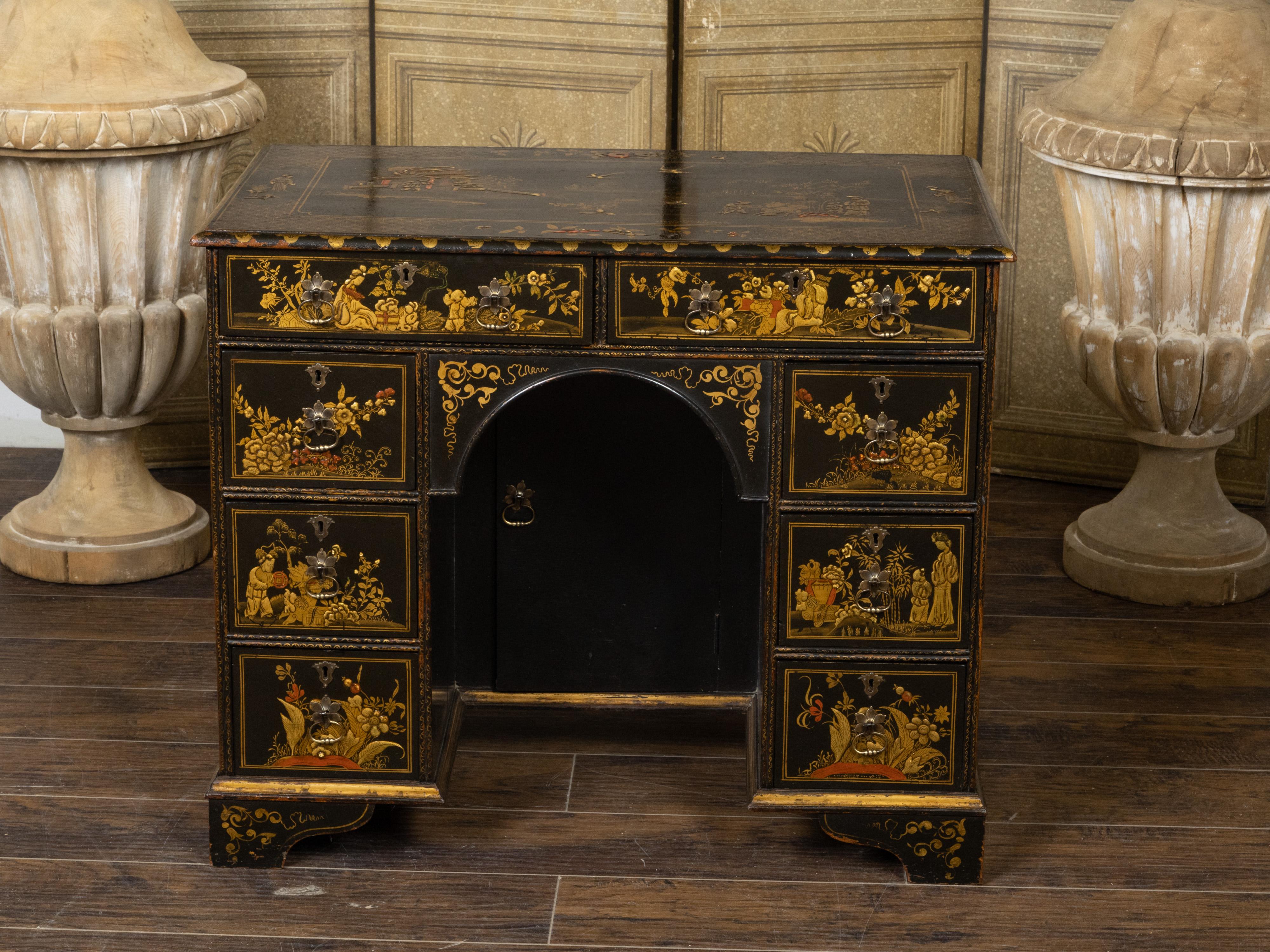 An English japanned kneehole desk from the 19th century with black and gold Chinoiserie décor, eight drawers and central door. Perfect to be used as a small desk or a dressing table, this English table from the 19th century captures our attention