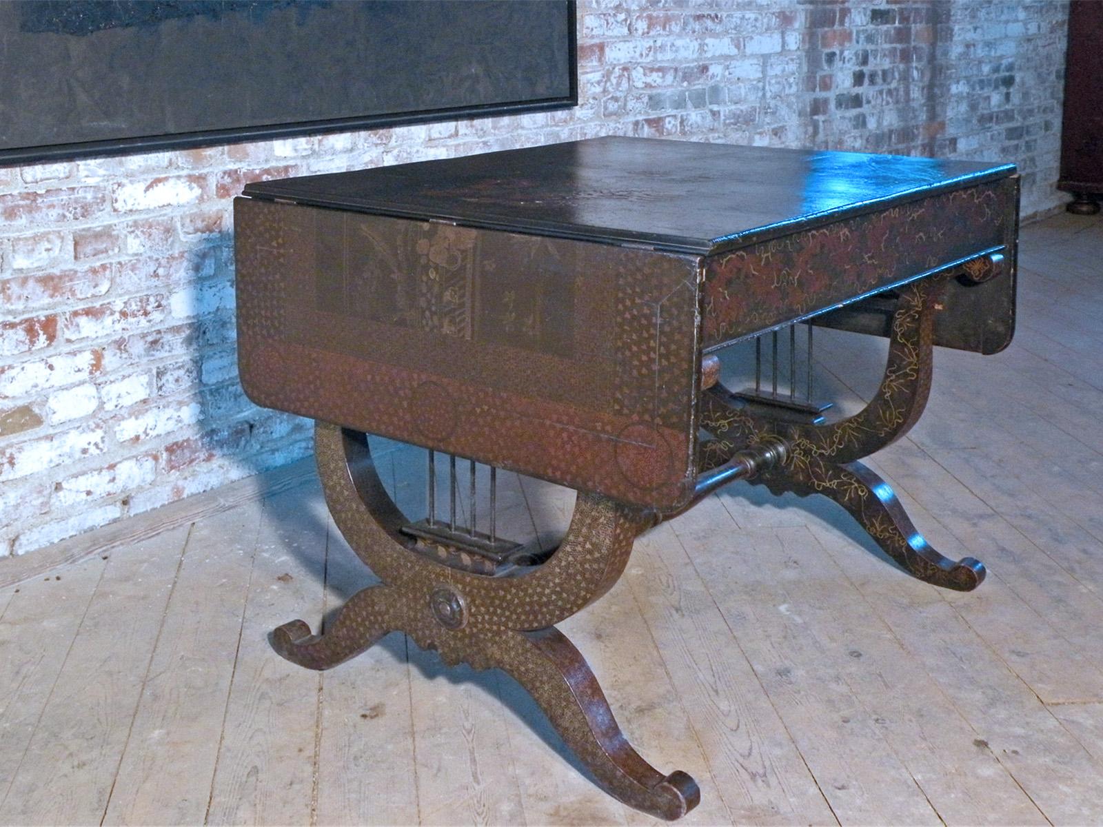 Unusual, English Late Regency Sofa Table with interesting Chinoiserie Decoration on a Black Lacquer background. The oblong top with drop-leaves at each end that are supported by swing-out brackets. The base consists of Lyre-shaped ends, connected by