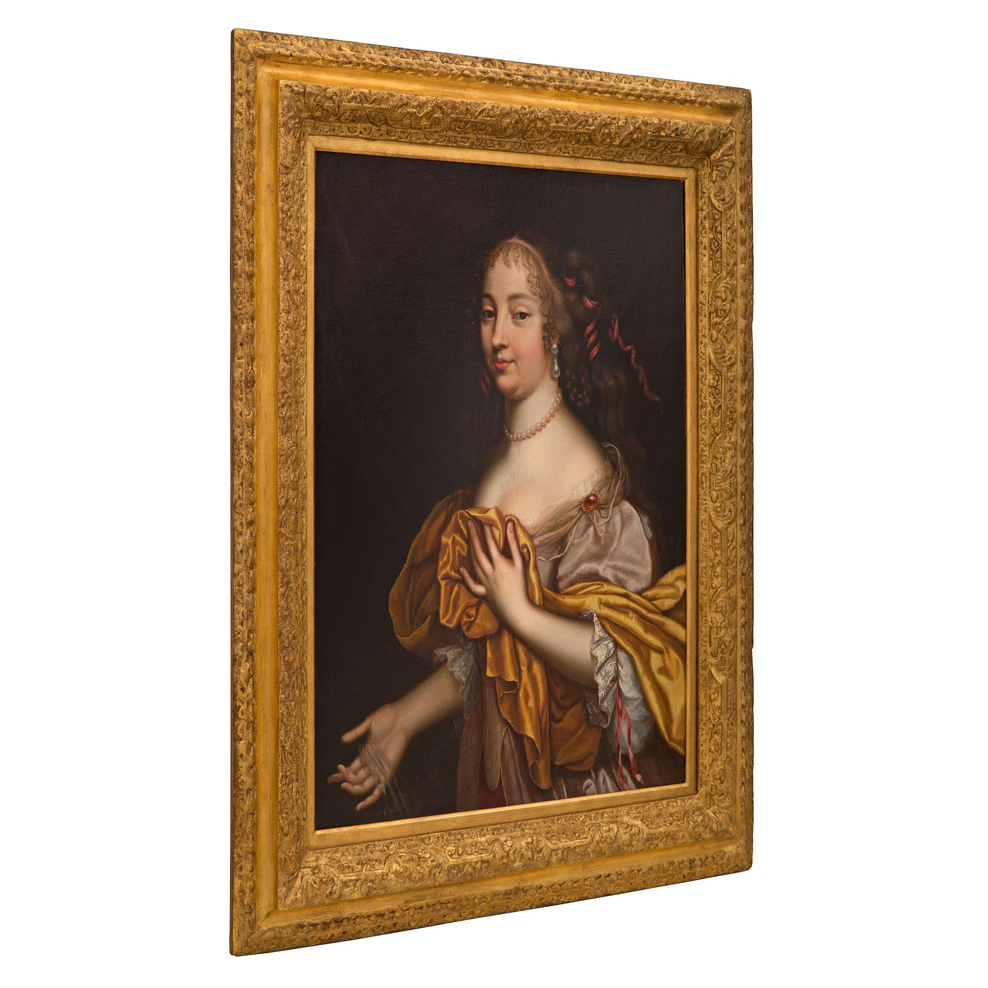 A beautiful and wonderfully executed English 19th century Louis XVI st. oil on canvas painting in the manner of Sir Peter Lely. The painting depicts a beautiful maiden dressed in an elegant flowing robe with a red jewel clasp. She is wearing an