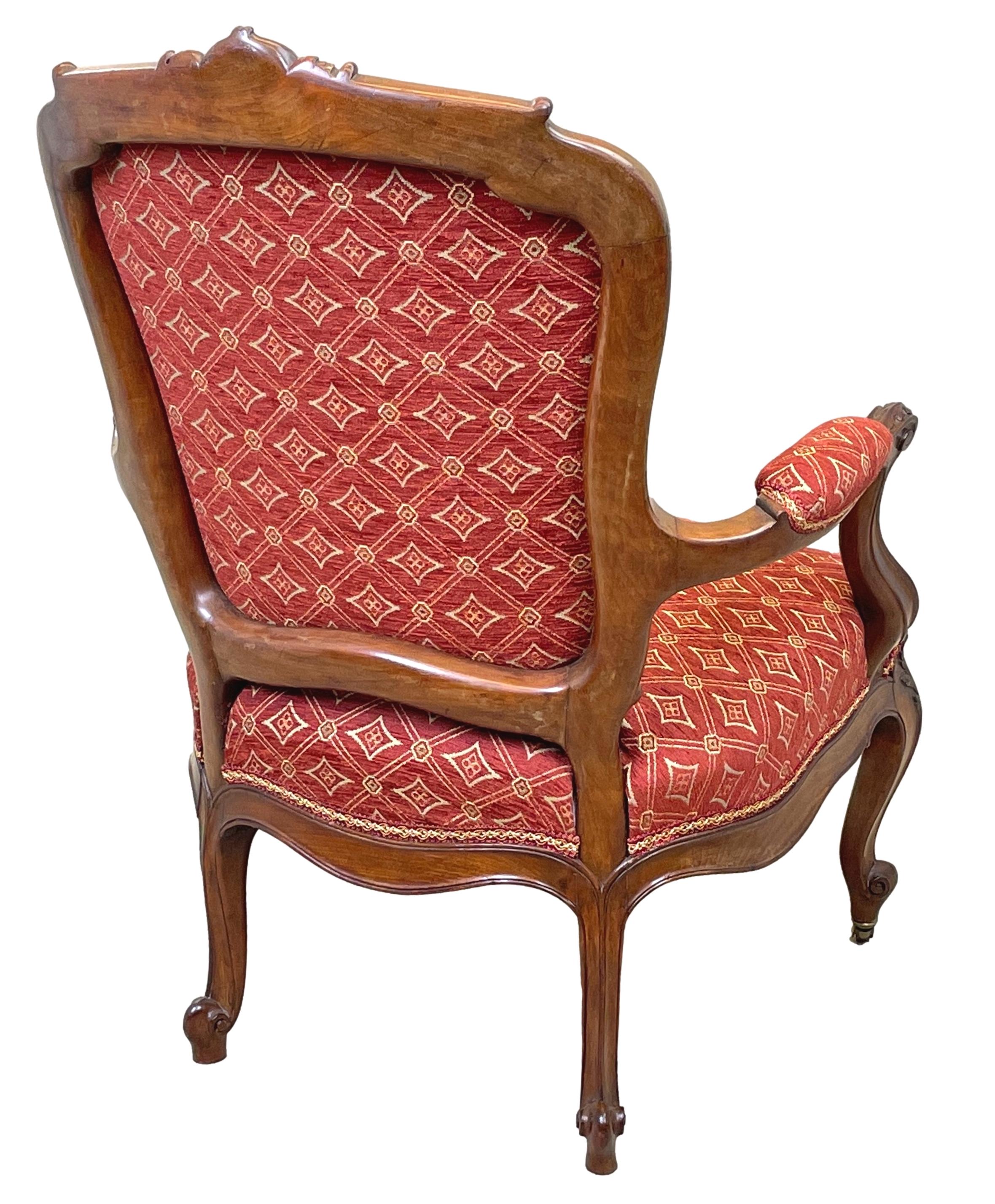 A very good quality mid 19th century English mahogany library armchair, in the French hepplewhite style, having central set carved cartouche to top rail over upholstered back and seat with elegant carved scrolling arms raised on moulded & carved