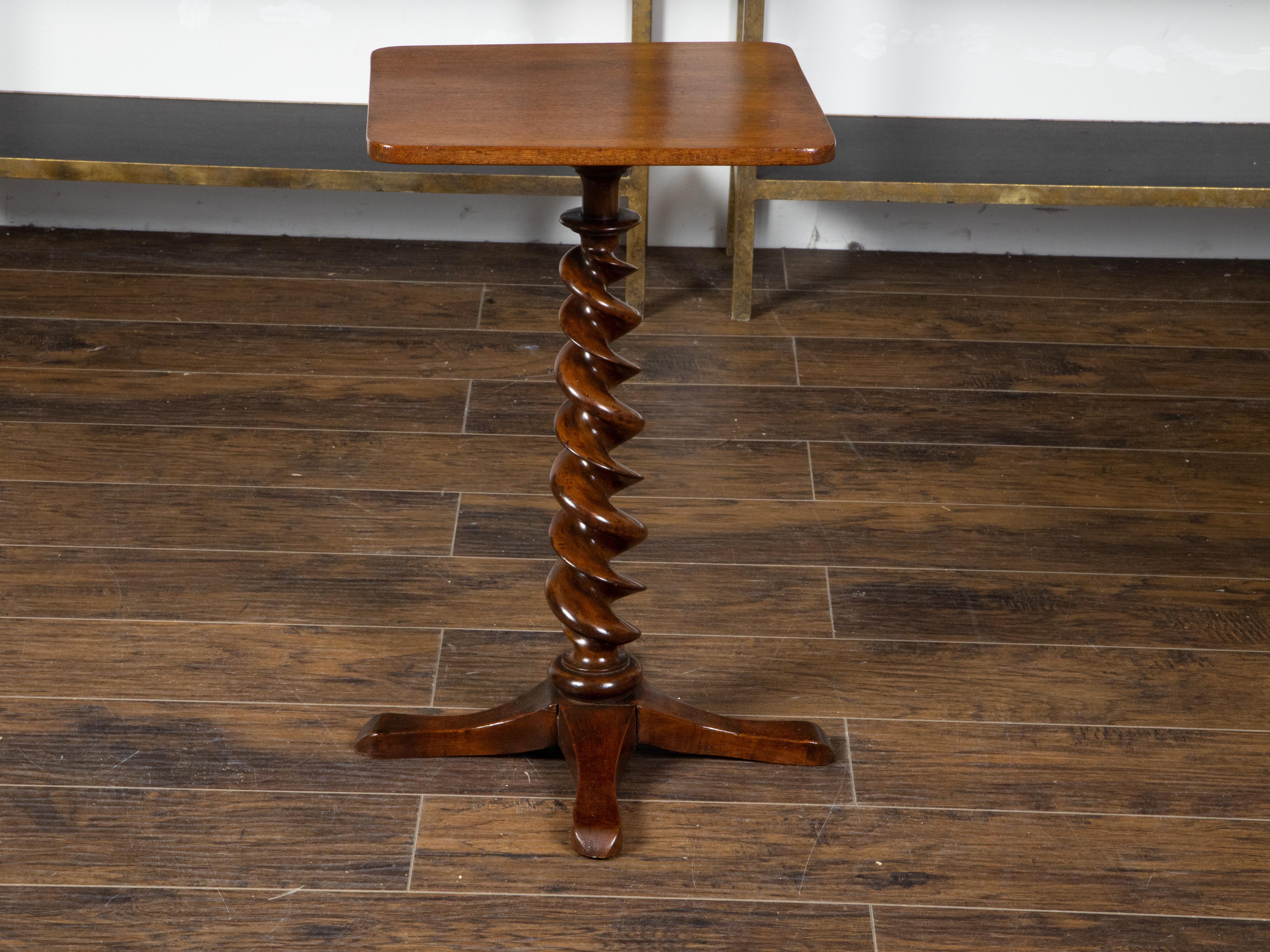 An English mahogany side table from the 19th century, with barley twist pedestal and quadripod base. Created in England during the 19th century, this mahogany side table features a square top sitting above a barley twist base resting on four
