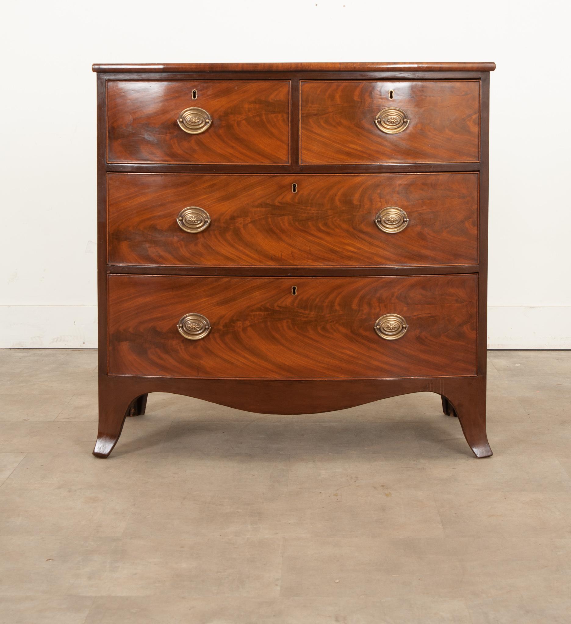 This is a splendid English 19th Century mahogany chest with a bow front. It has a beautiful patina from years of loving care and use. The top sits over four drawers, each with handsome oval brass pulls. All sit atop four splayed legs. Circa 1860. Be