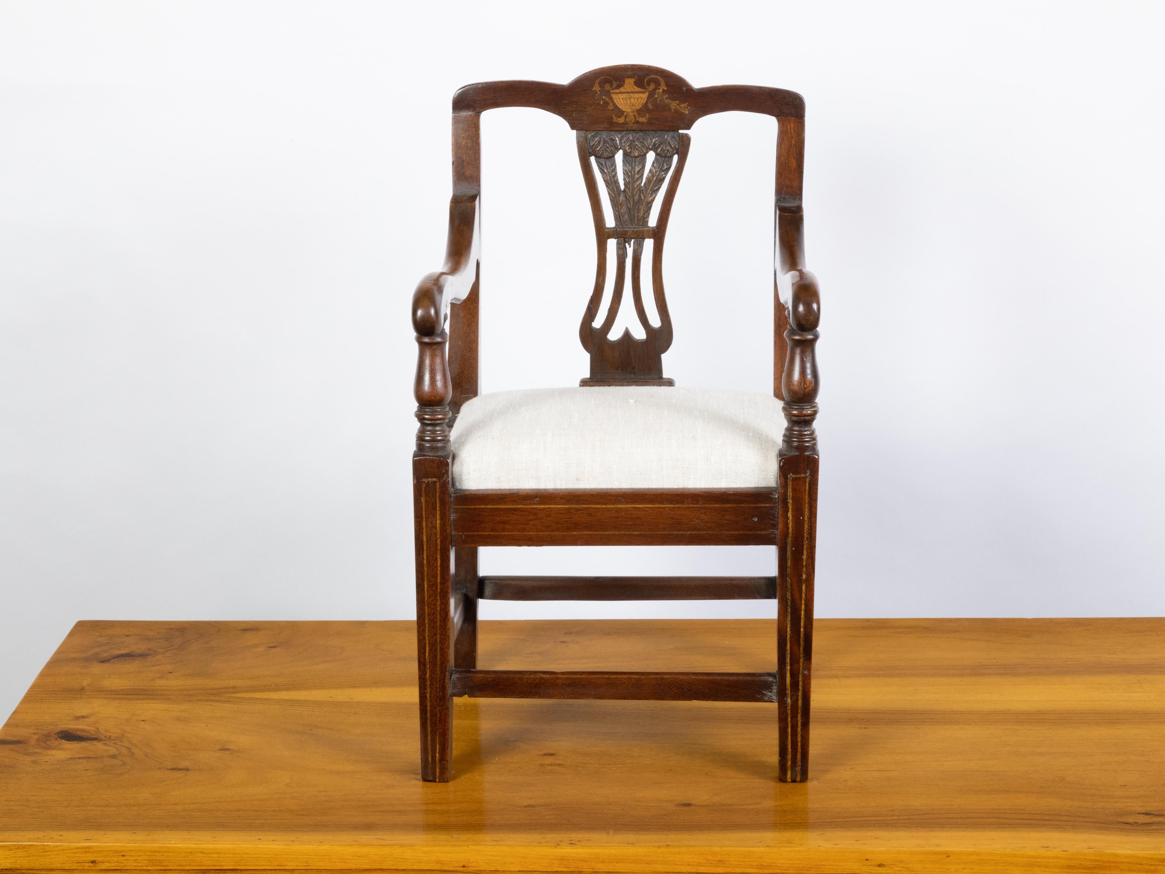 An English mahogany child's chair from the 19th century, with feather motifs and marquetry décor. Created in England during the 19th century, this petite chair features an open back adorned with feather motifs on the splat, and an urn marquetry on