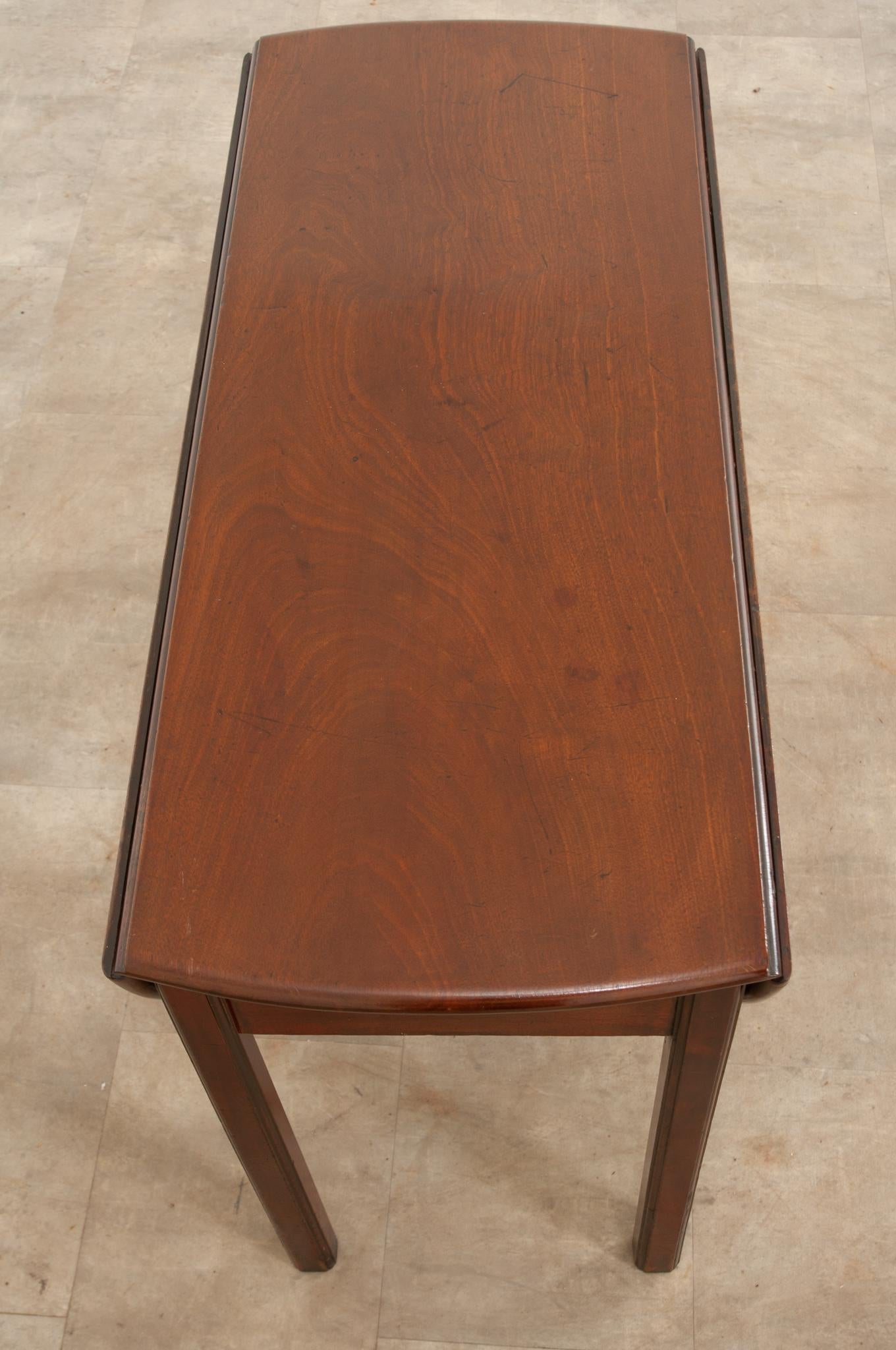 A fantastic English mahogany drop leaf table, made there circa 1840. The table has two large, demilune-shaped leaves that lay to the sides of the table when down. To expand the top and raise the leaves, the leaves are lifted, and the apron itself is