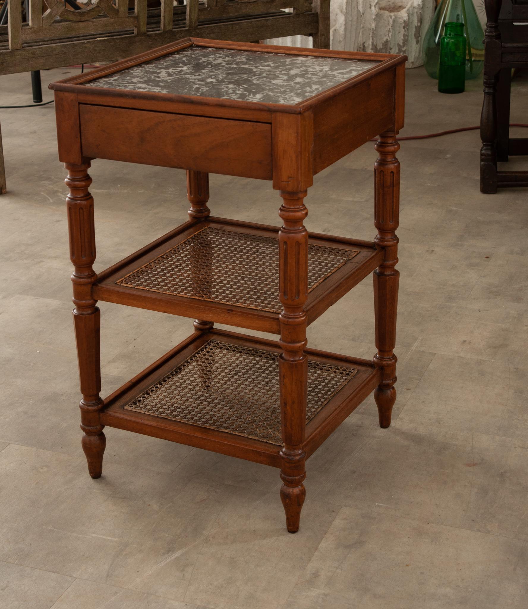 An elegant 19th century English etagere. Hand-crafted in France circa 1870 and built of walnut, the square table stands on finely turned baluster legs ending with arrow feet.  Connected at the base are two cane shelves over a straight plain apron