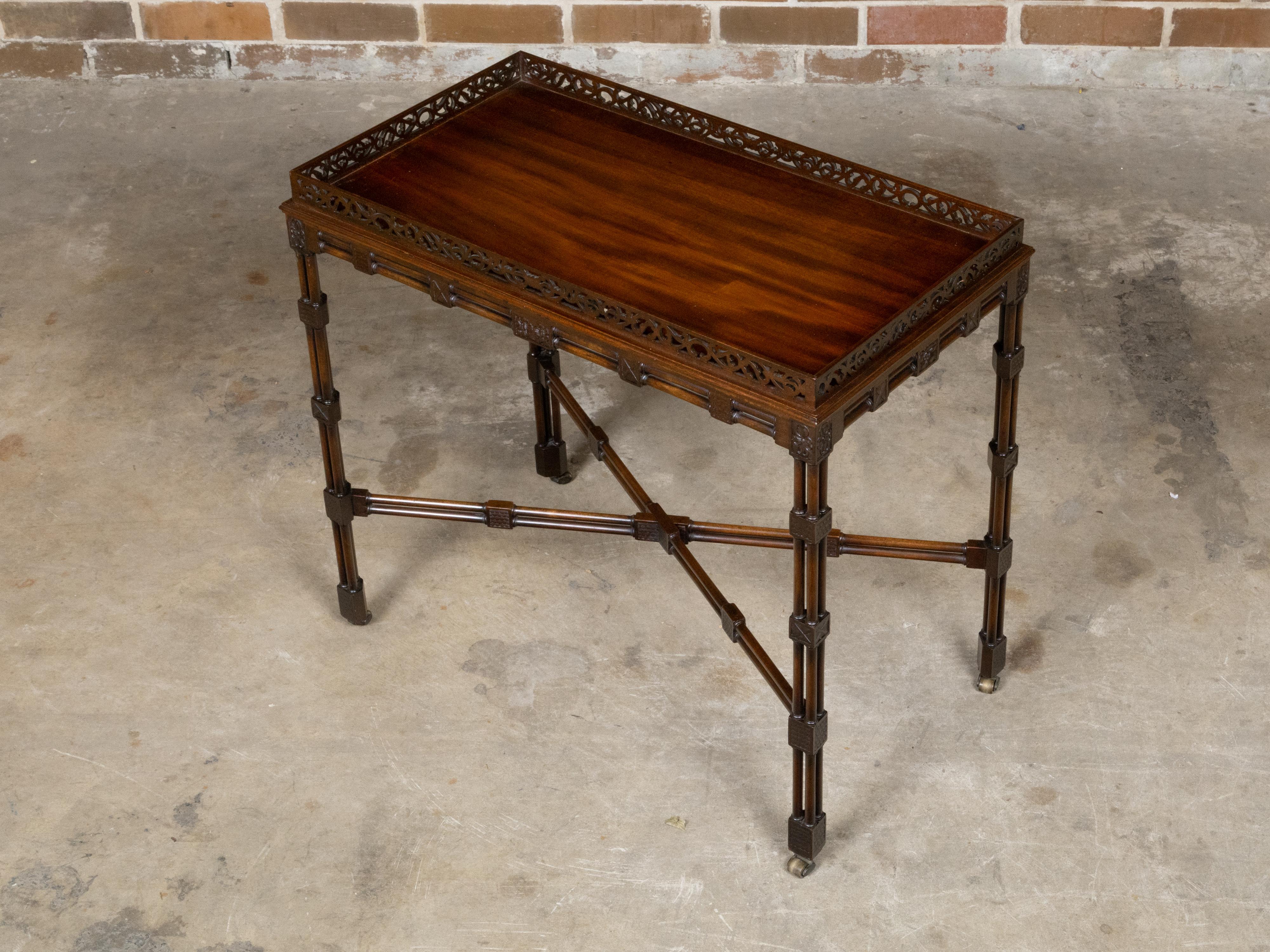 Table d'appoint anglaise en acajou du XIXe siècle avec plateau sculpté, base en faux bambou, traverse, rosaces et roulettes. Cette exquise table d'appoint en acajou anglais du XIXe siècle présente une galerie percée sur les quatre côtés, ornée de