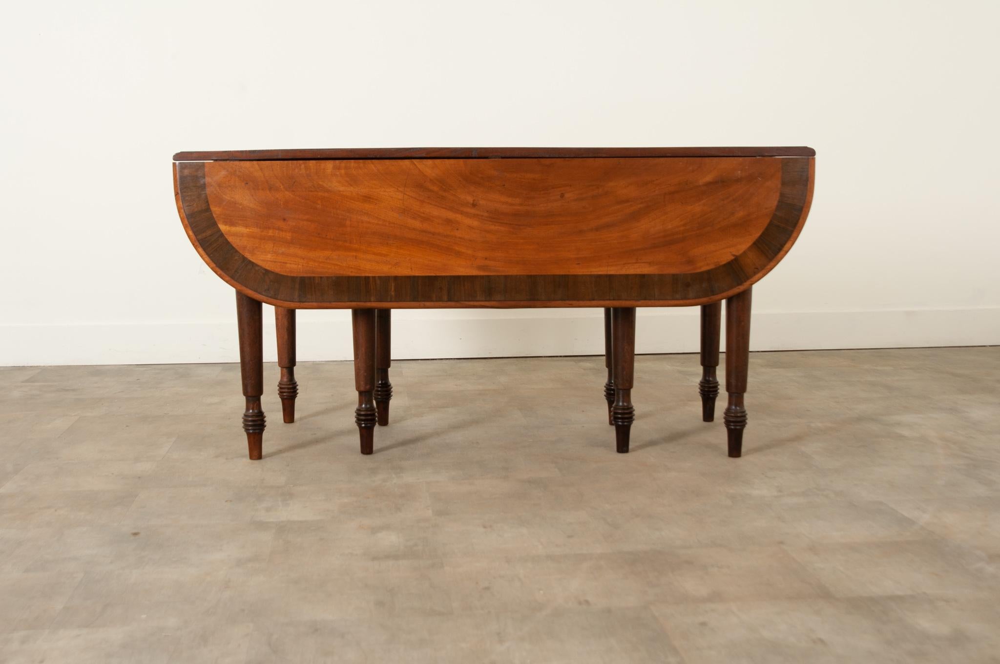 A stand-out English mahogany gateleg drop-leaf table, hand-crafted in England in the 19th Century. Attractive in color with well proportioned rounded corner drop leaves and a good folding mechanism. The beautiful flame mahogany top is edged in a