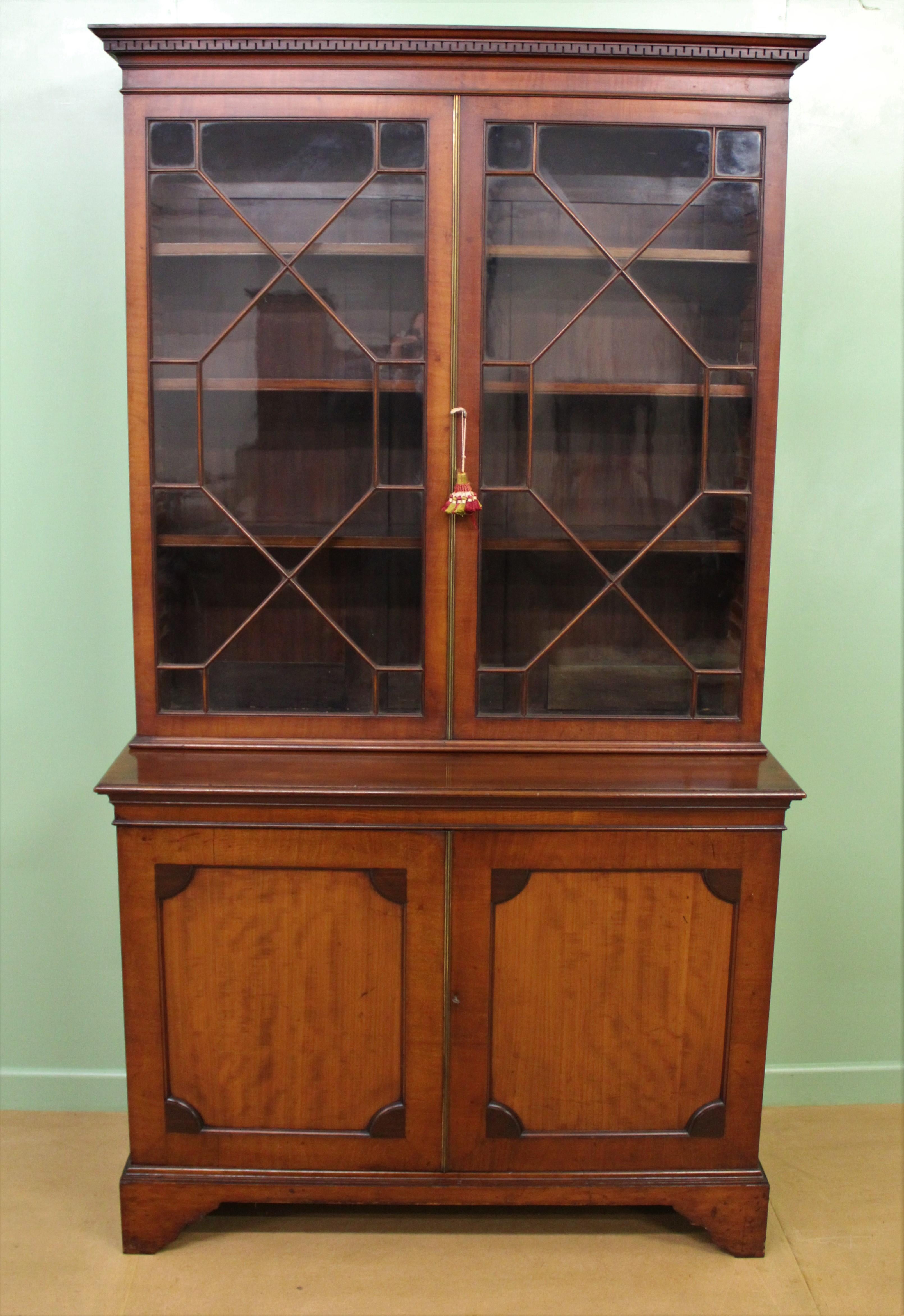 A very good glazed mahogany two door bookcase. Very well constructed in solid mahogany with attractive mahogany veneers. The top section with a dentil molding cornice sitting over a pair of glazed doors. The doors open to access an interior with
