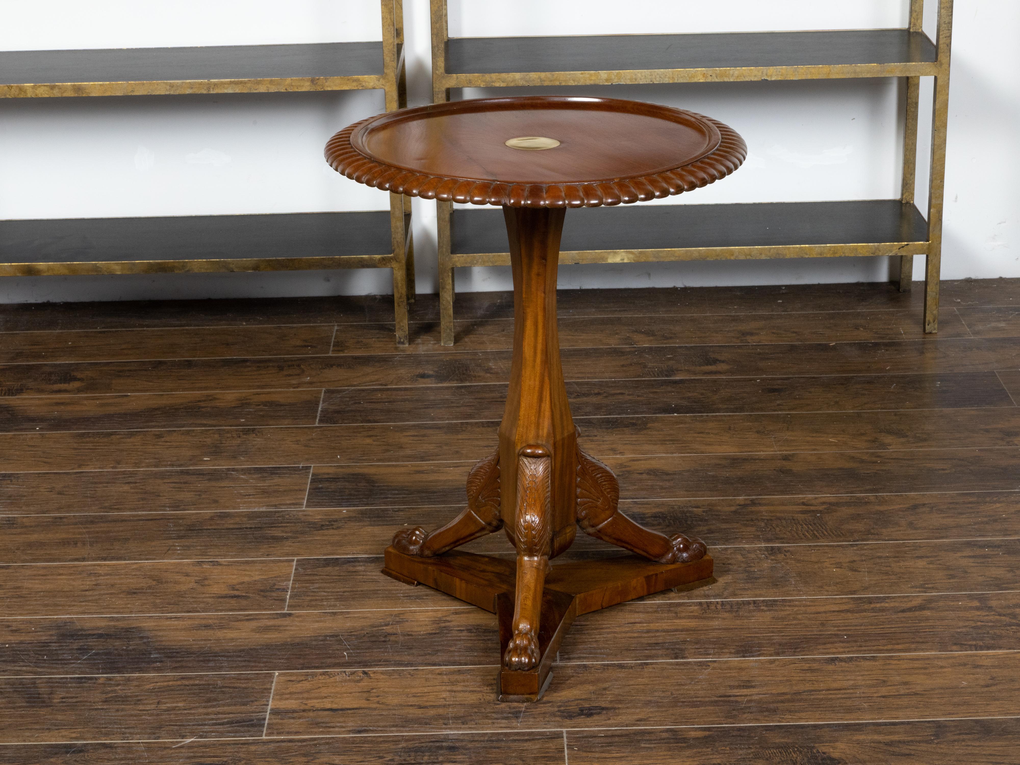 An English mahogany guéridon pedestal side table from the 19th century with brass inlay, gadroon motifs and carved griffin legs. Created in England during the 19th century, this mahogany guéridon side table features a circular top with recessed