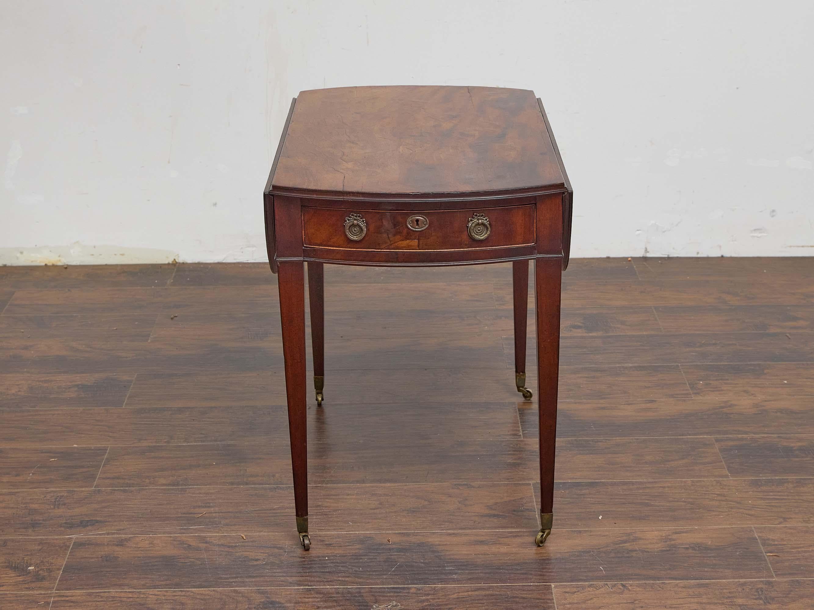 Cette table Pembroke en acajou anglais du XIXe siècle est un exemple raffiné d'élégance fonctionnelle. Le plateau est fabriqué en acajou richement figuré, avec une patine chaude et bien développée. Il est équipé de deux feuilles tombantes articulées