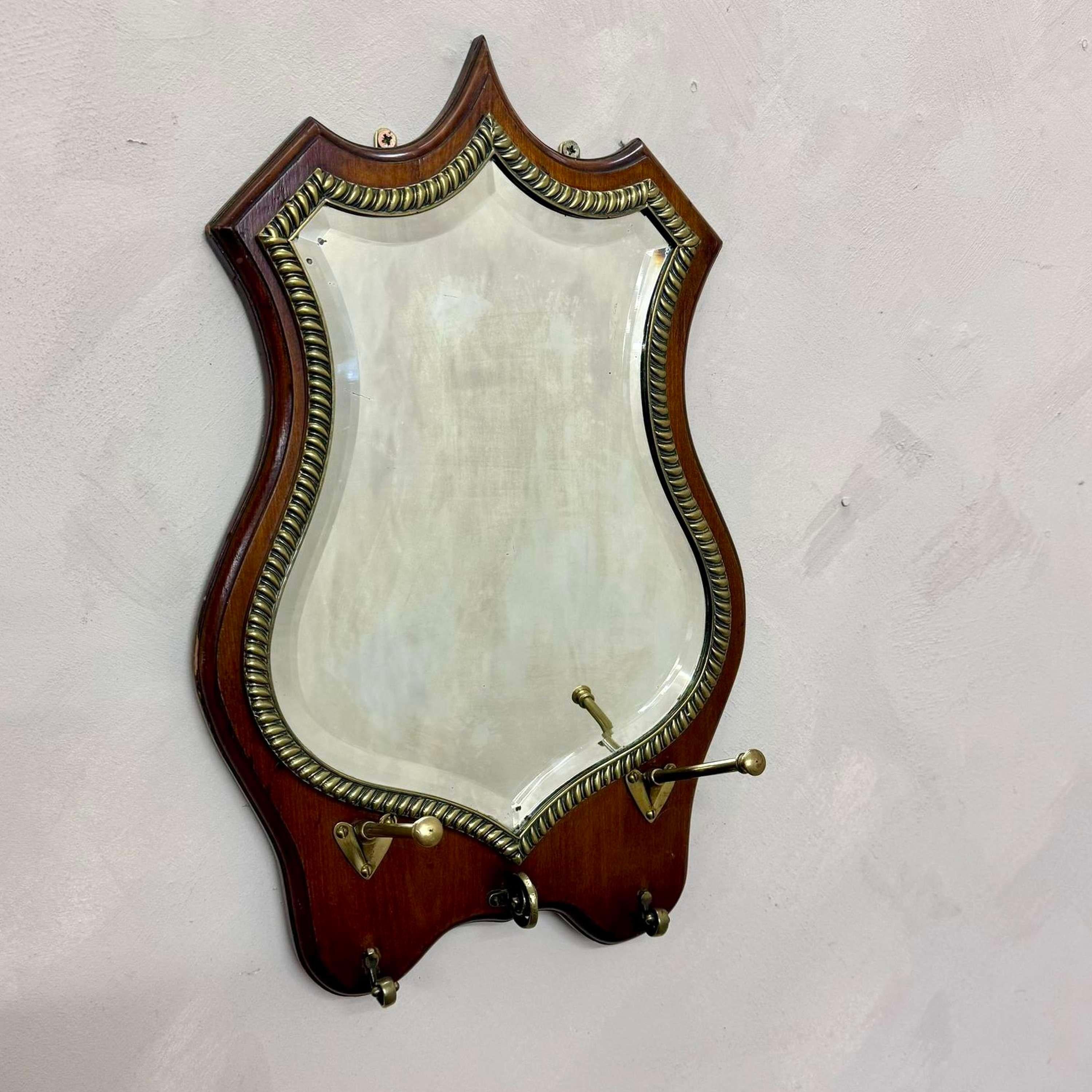 Mahogany framed Shield Mirror, with original bevelled plate.
With brass gadrooning detail and hat and key hooks.

England, circa 1890.
Dimensions:W: 34cm (13.4
