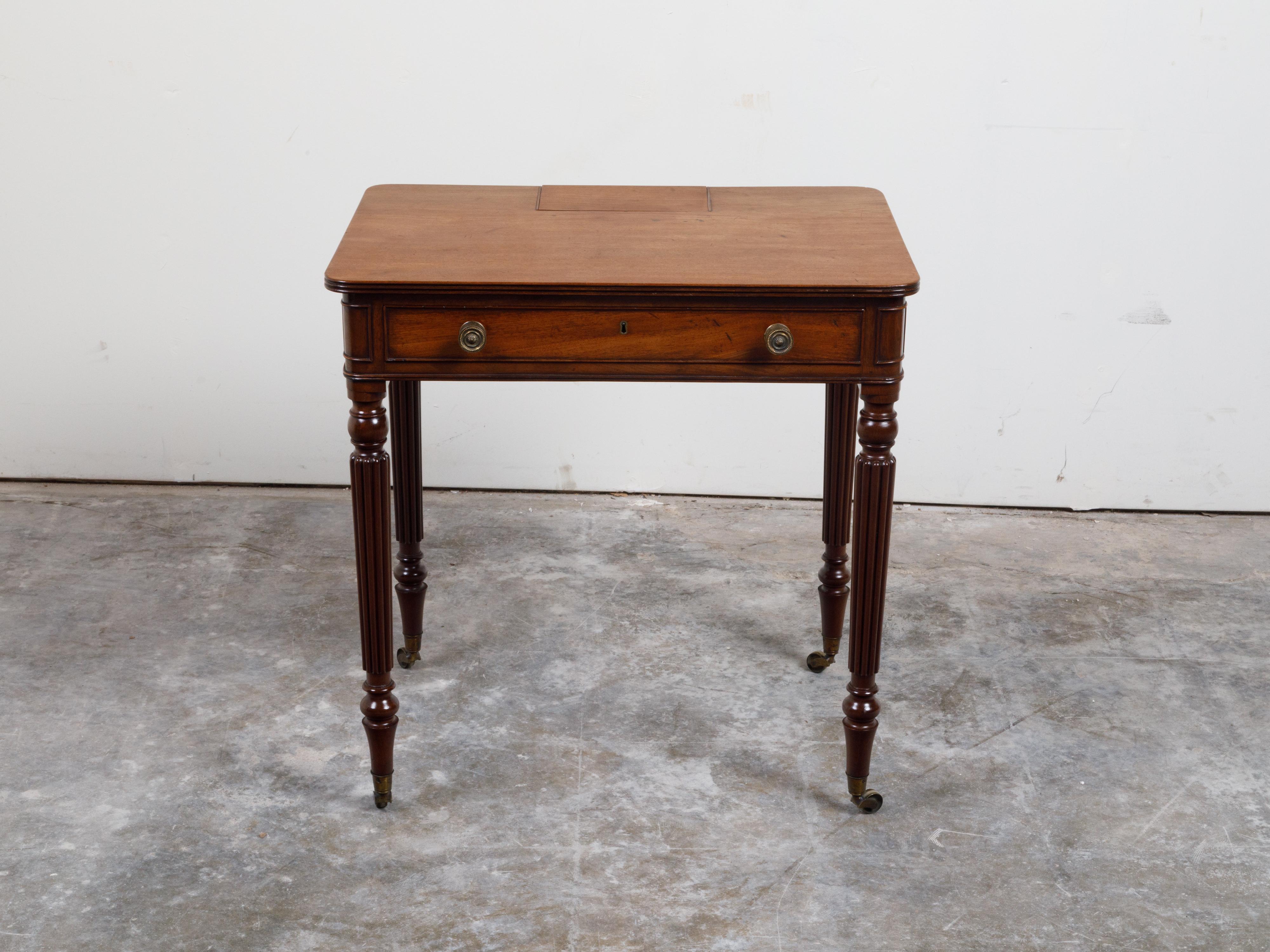 Une table anglaise en acajou du 19ème siècle, avec un seul tiroir, un petit compartiment et des pieds cannelés. Créée en Angleterre au cours du XIXe siècle, cette table en acajou présente un plateau rectangulaire aux coins arrondis et un petit