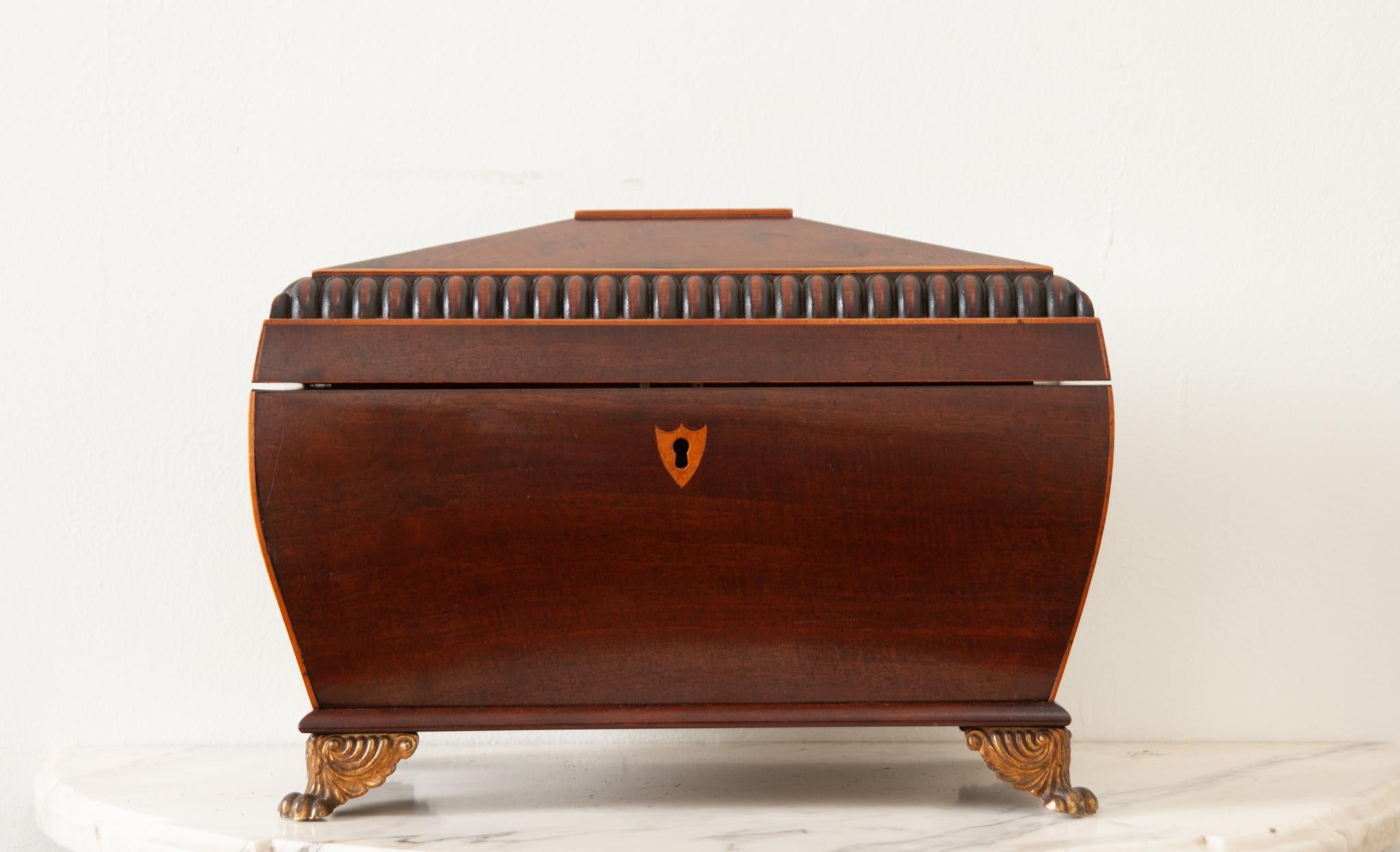 An English 19th Century top quality, solid mahogany tea caddy. This shaped box has a carved angular top lined with satinwood opening to a fitted interior. There are two removable fitted compartments with sliding tops once used for storing loose leaf