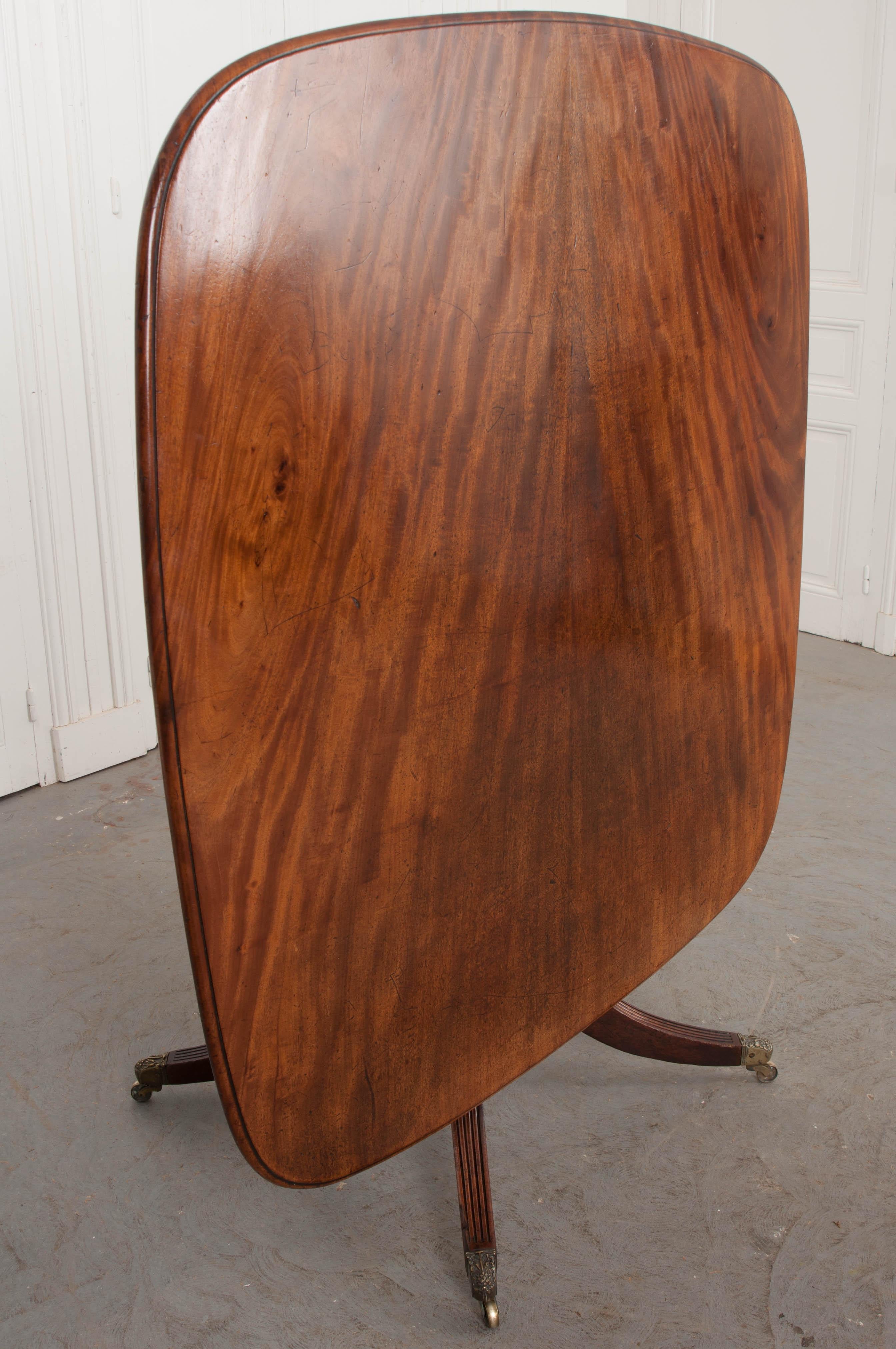 This fine English mahogany tilt-top center table is signed and dated “T.O. Beeman, 1849,” on the underside. The surface, of almost square section, has gorgeous book-matched mahogany veneer, rounded corners and tilts for storage when not in use. The