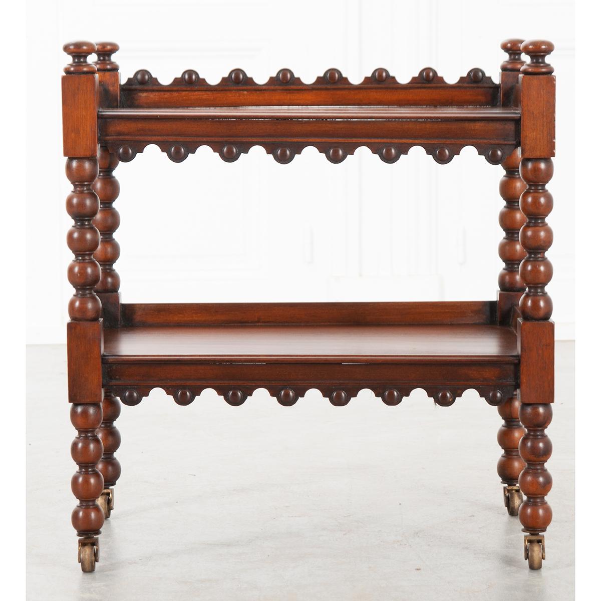 This is a wonderful two-tier mahogany tea trolley, circa 1880. It is a much smaller version of the traditional piece. It features a scalloped edge across the top of the back and the bottom of both shelves. The color is very rich and the patina is