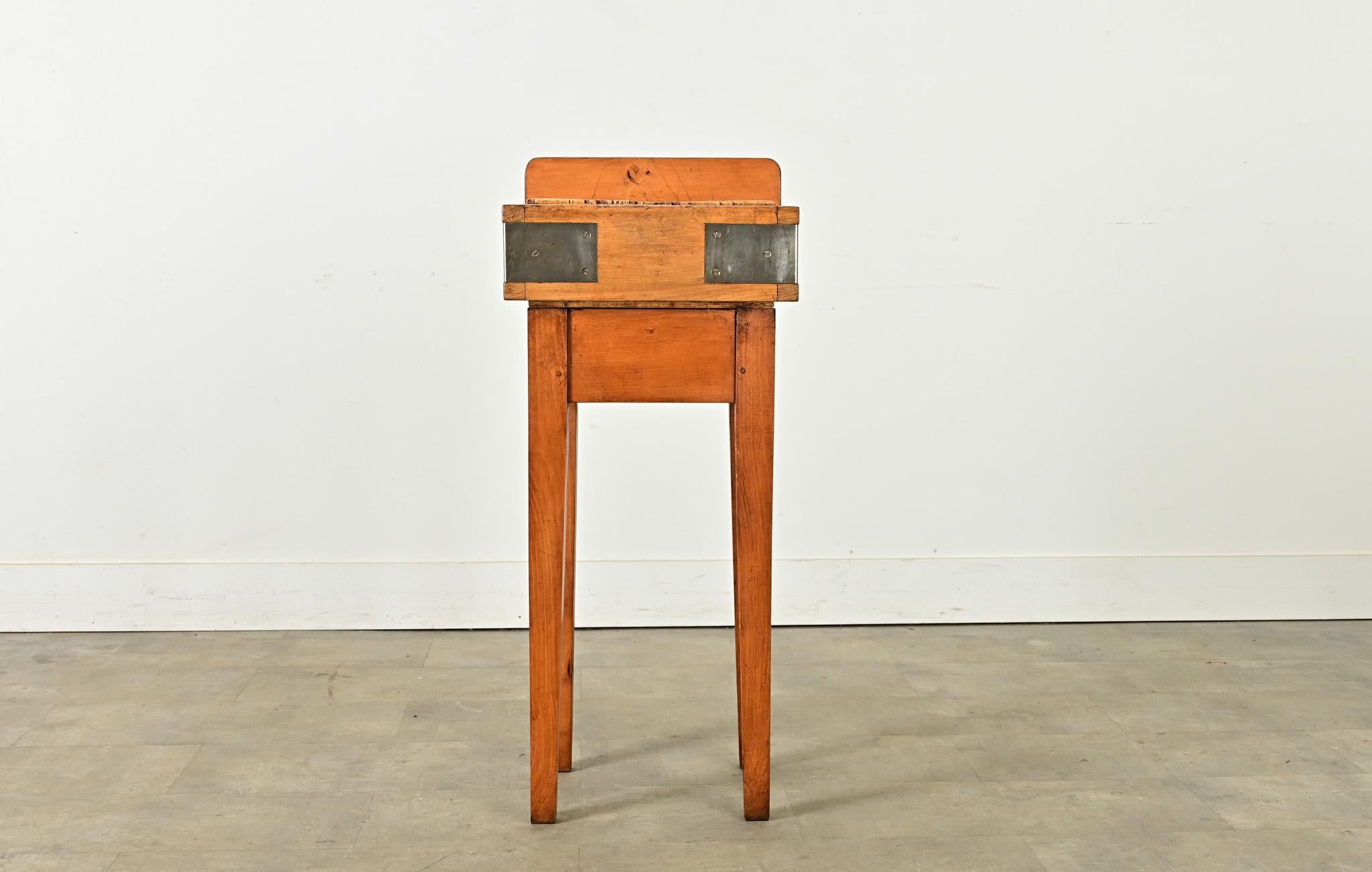 A petite English butcher block table made from maple, dating to the 1800’s. It has a thick work surface, well-patinated from time and use, protected on the back by a raised edge. There is a steel knife slot along the back to keep one’s preferred
