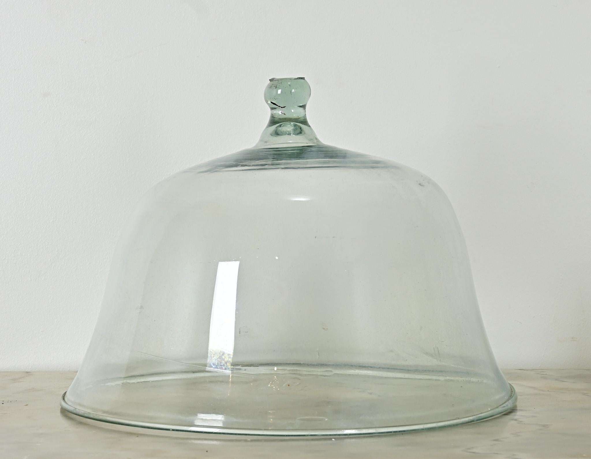 Originally intended to function as a protective greenhouse for young melons developing on the vine, this 19th century English Melon Cloche is formed in a single, heavy piece of clear glass with a solid knob handle. Creating such a large dome by hand