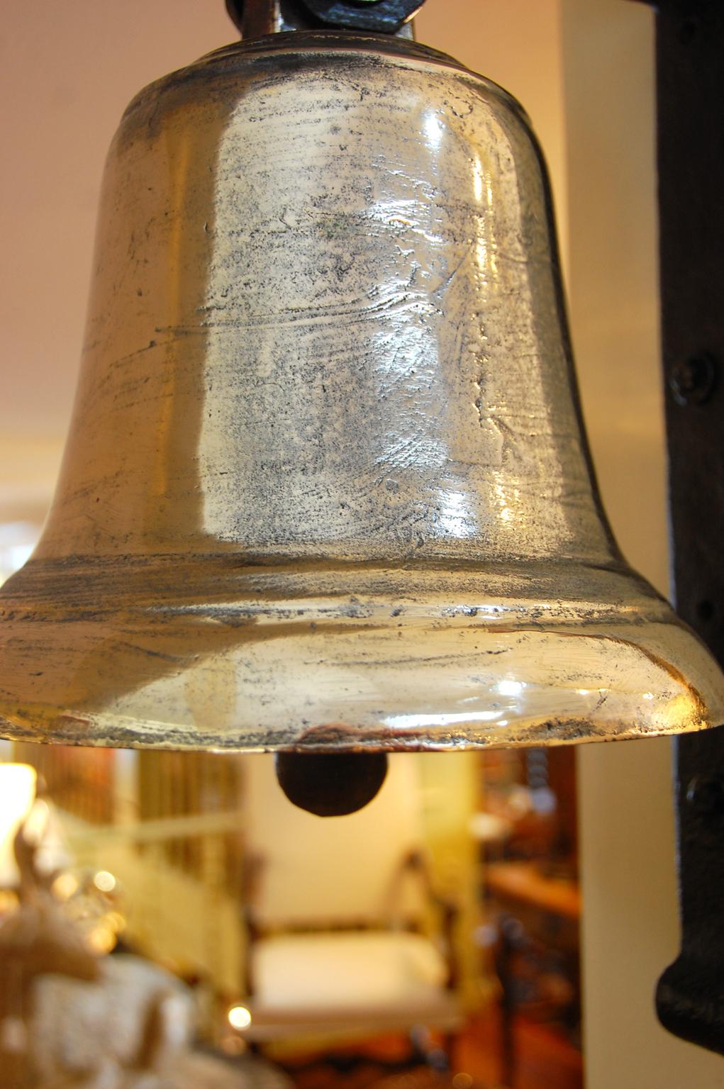 English 19th century military hanging bell in cast bell metal, iron clapper; a clear sound that carries well makes this a joy to hear. The holder for the bell has been made from an 18th century American barn door hinge of unusually thick iron, so