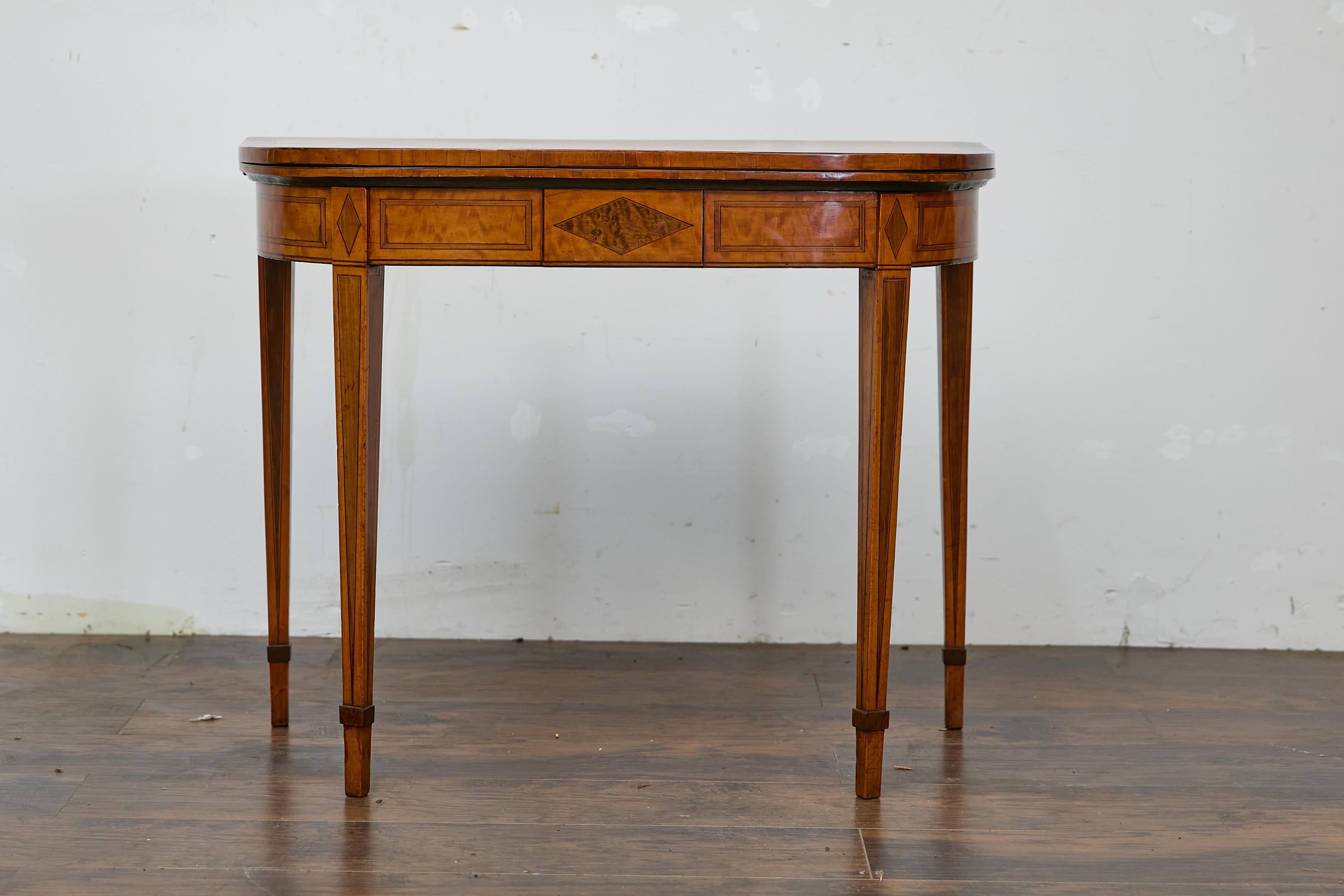 An English Neoclassical demi-lune game table from the 19th century with flip top and inlaid diamond décor. This English Neoclassical demi-lune game table from the 19th century captures our attention with its refined silhouette and elegant inlaid